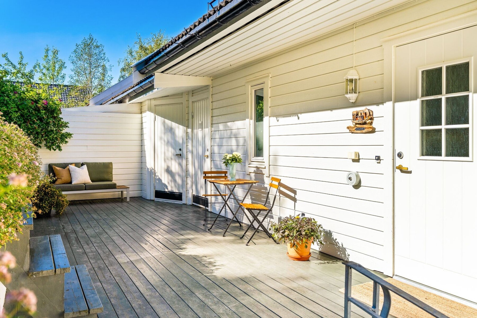 Hyggelig uteplass ved inngangen som nyter godt av morgen og formiddagssola. Inngang til bod og nedgang til garasjen. Galleribilde