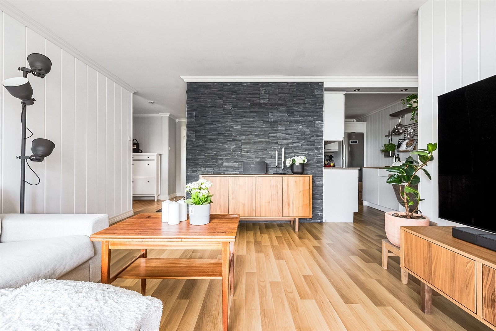 Stuen har laminat på gulv, lyse overflater malt i 2024/25 og en kontrastvegg dekorert med fasadestein. Galleribilde