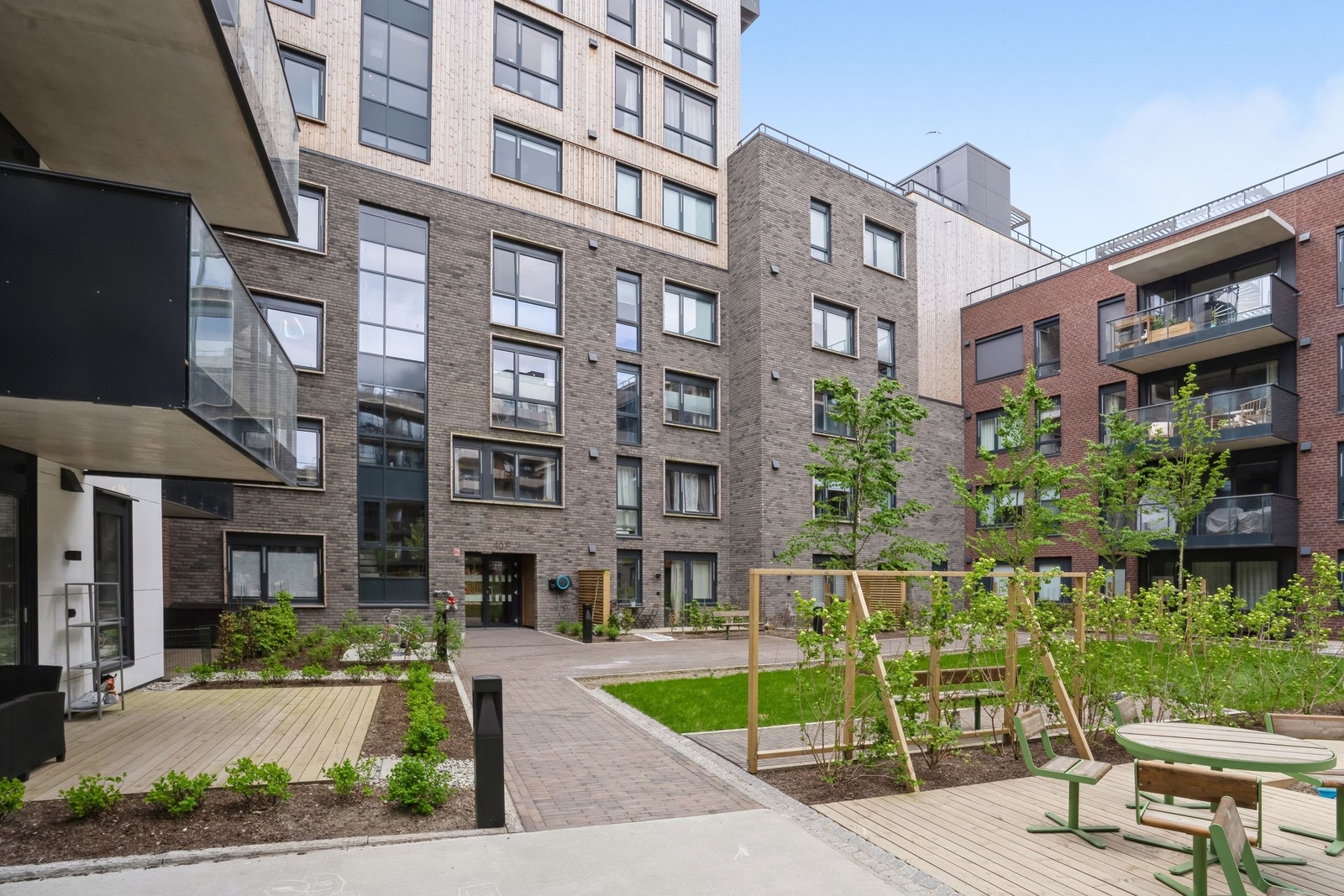 Terrassen ligger ut mot bakgård med felles lekeplass og gressplener. Galleribilde