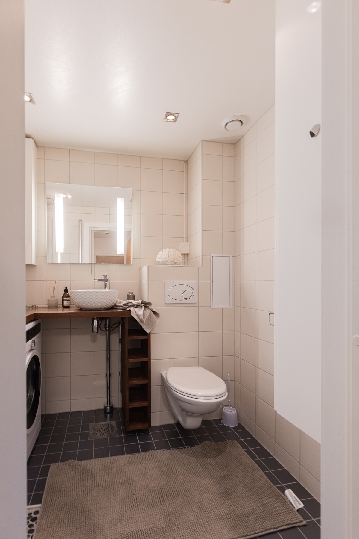 Vegghengt toalett, rund servant på benkeplate, speil og gode oppbevaringsløsninger med overskap. Galleribilde