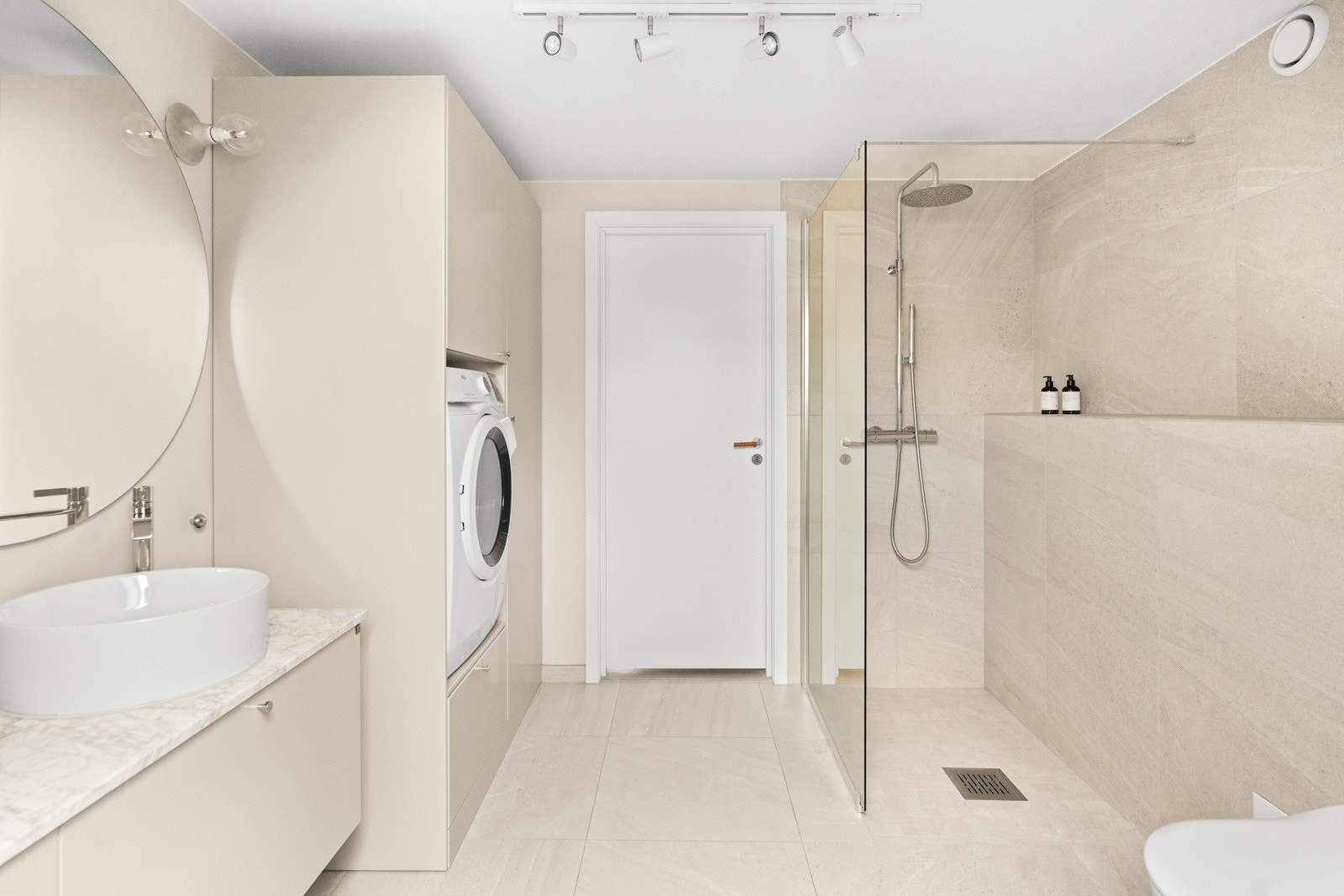 Badet består av vegghengt toalett, servant med slette fronter, dusjhjørne og opplegg for vaskemaskin. Galleribilde