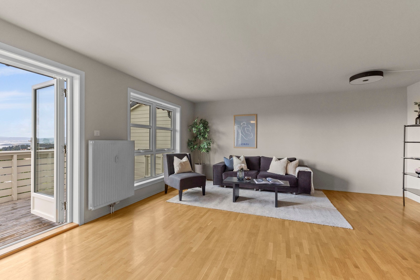 Lys og innbydende stue med lyse flater og trestavs parkett på gulv. Galleribilde