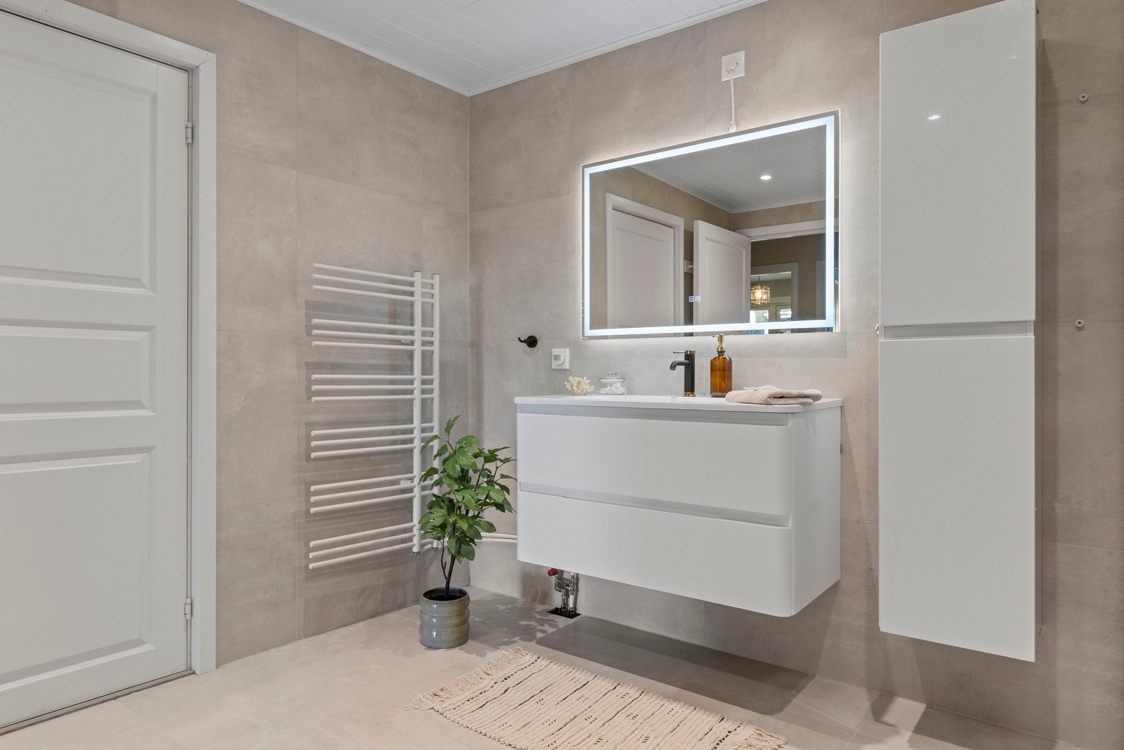 Badet fremstår eksklusivt med store fliser, moderne innredning og stilrene detaljer. Galleribilde