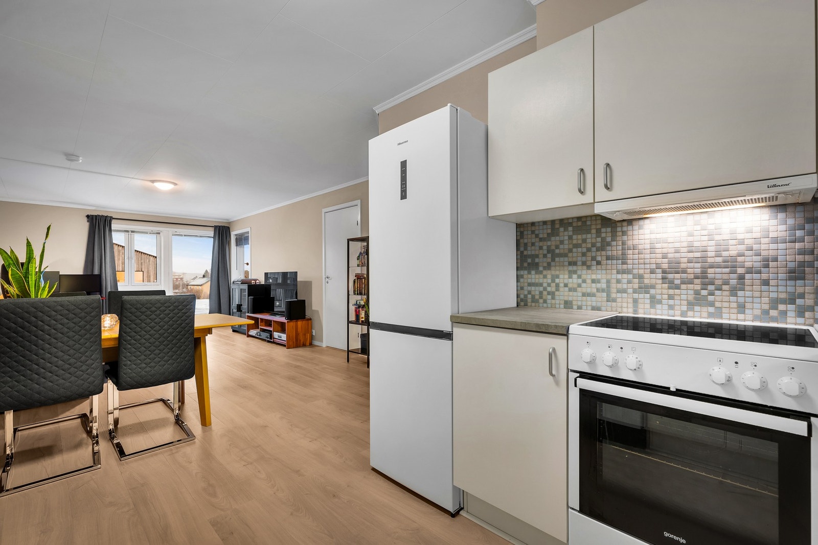 Videre er kjøkken utført med laminert benkeplate, flis på vegg over kjøkkenbenk og integrert ventilator. Galleribilde