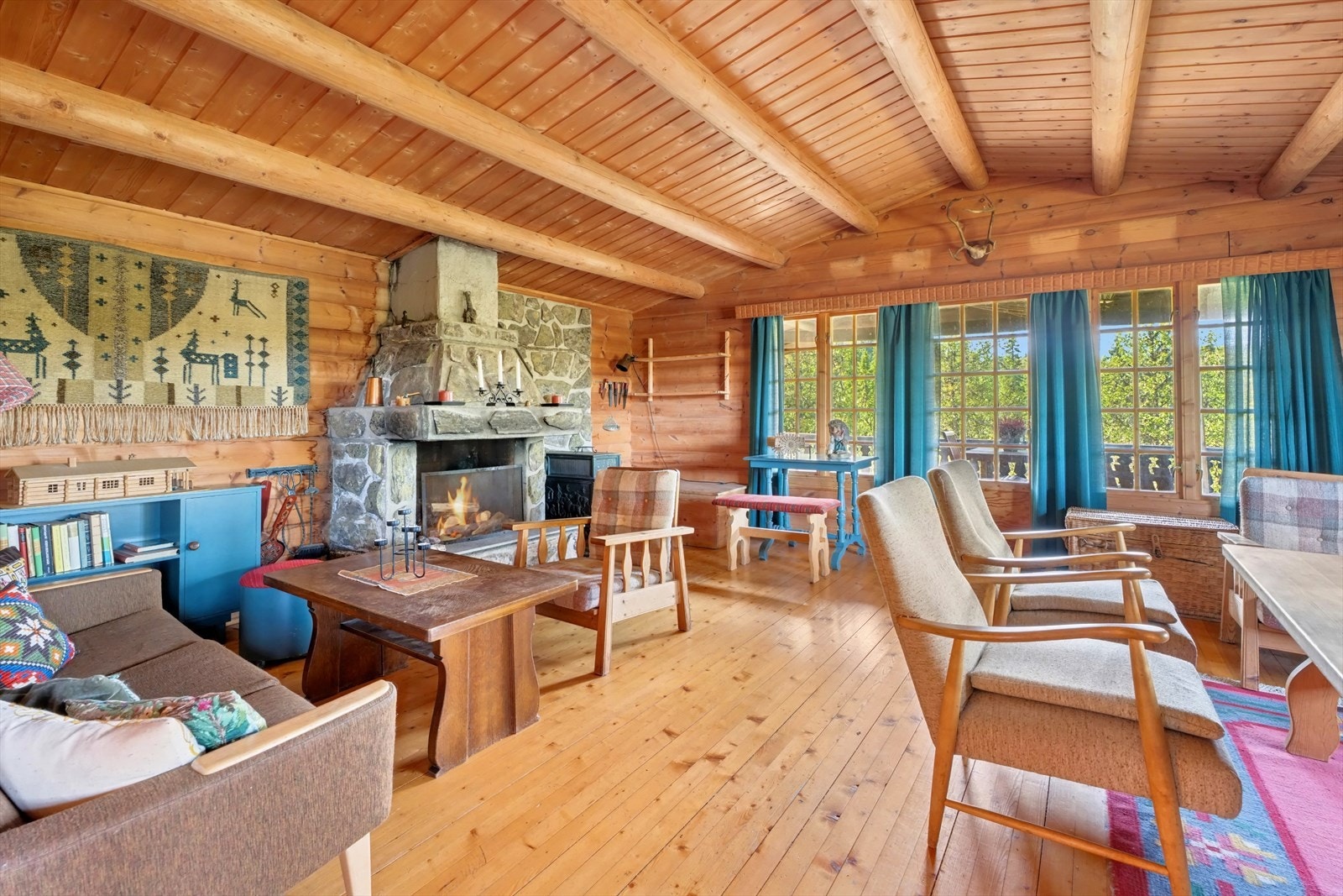 Romslig stue med høy takhimling og synlige tømmeråser. Galleribilde