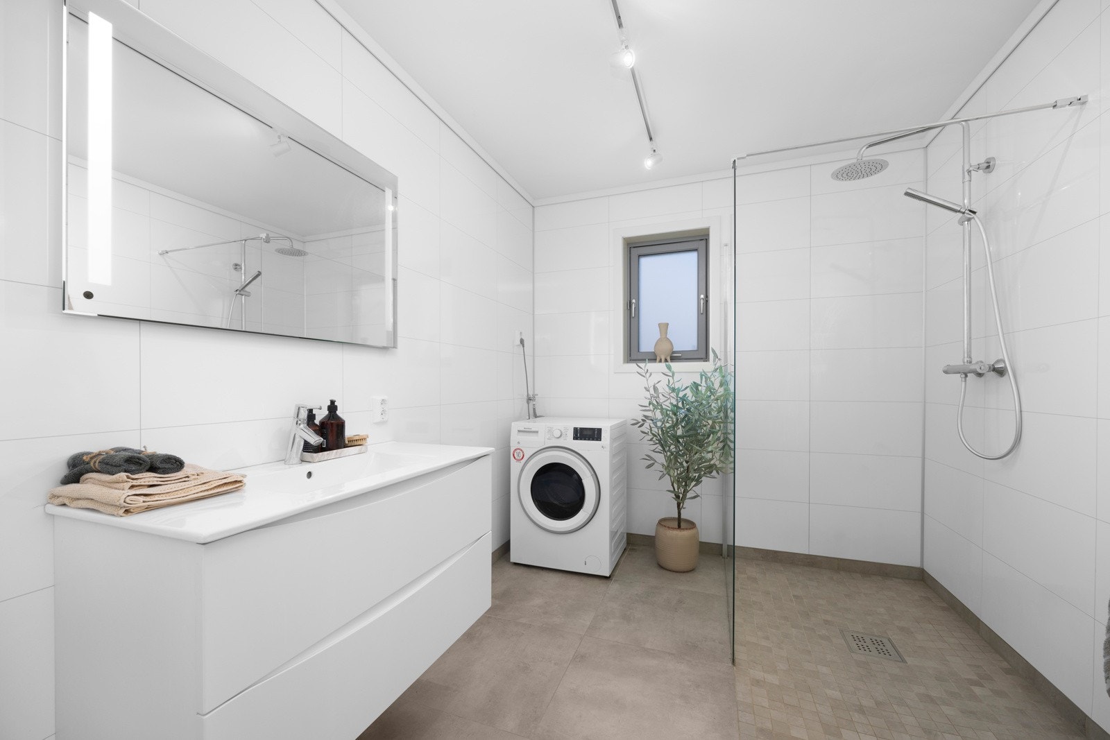 Leiligheten har et romslig bad med god plass, opplegg til vaskemaskin og dusjnisje med glassvegger Galleribilde