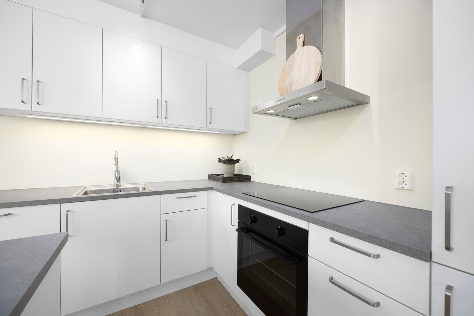 Kjøkkeninnredning fra Strai med glatte og lyse fronter og en laminat benkeplate i stilren farge som står til frontene Galleribilde