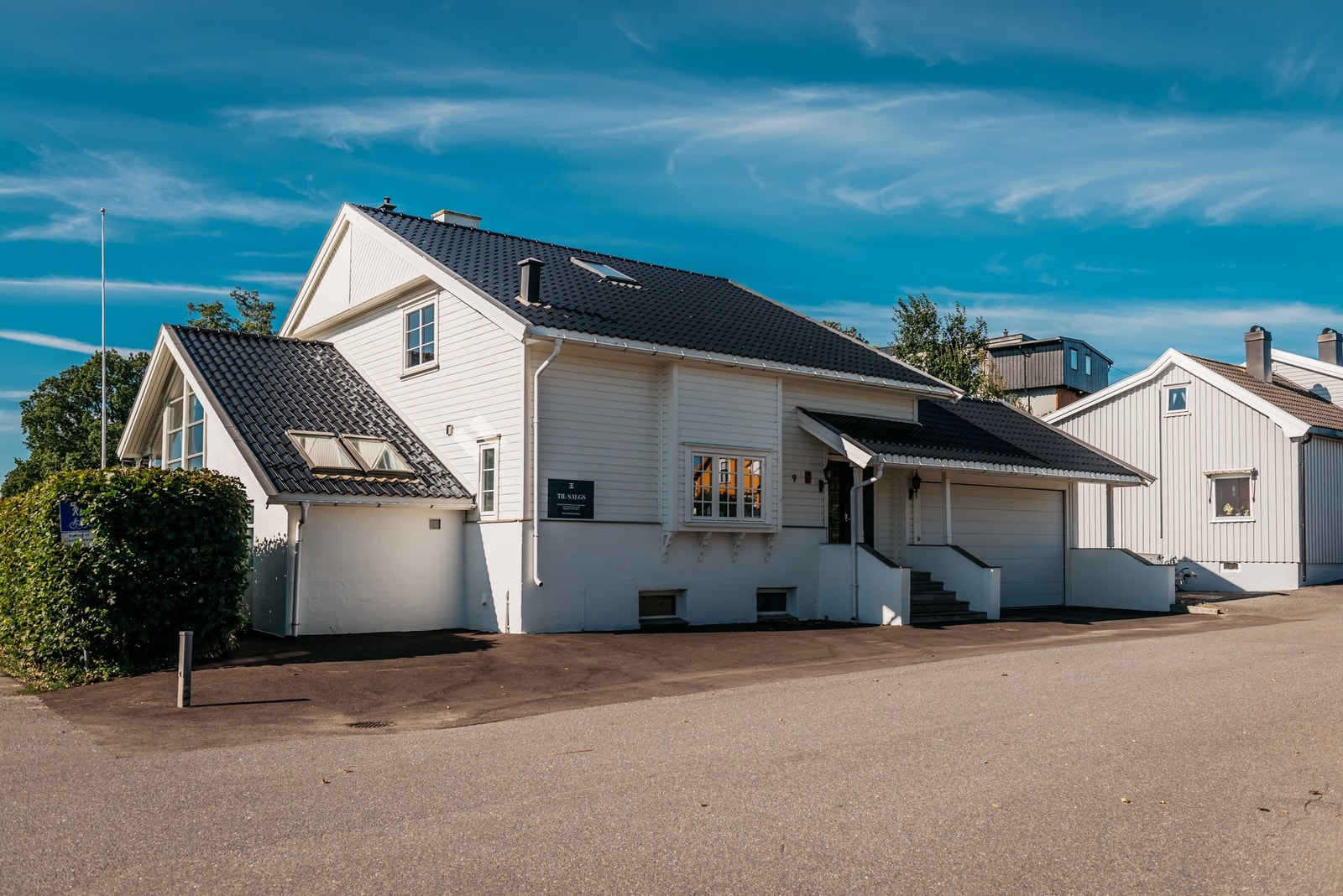 Fasade i front, med dobbelgarasje og noe gårdsplass. Galleribilde