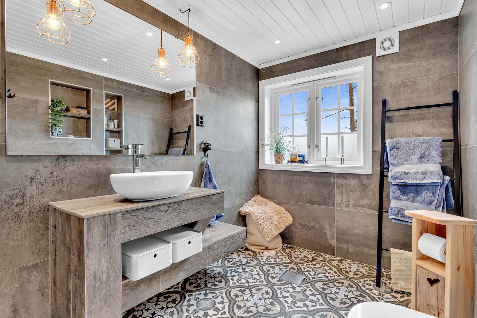 Gulvet er flislagt med gulvvarme, som gjør det ekstra behagelig på kalde morgener, og veggene er flislagt for et tidløst og rent uttrykk. Galleribilde