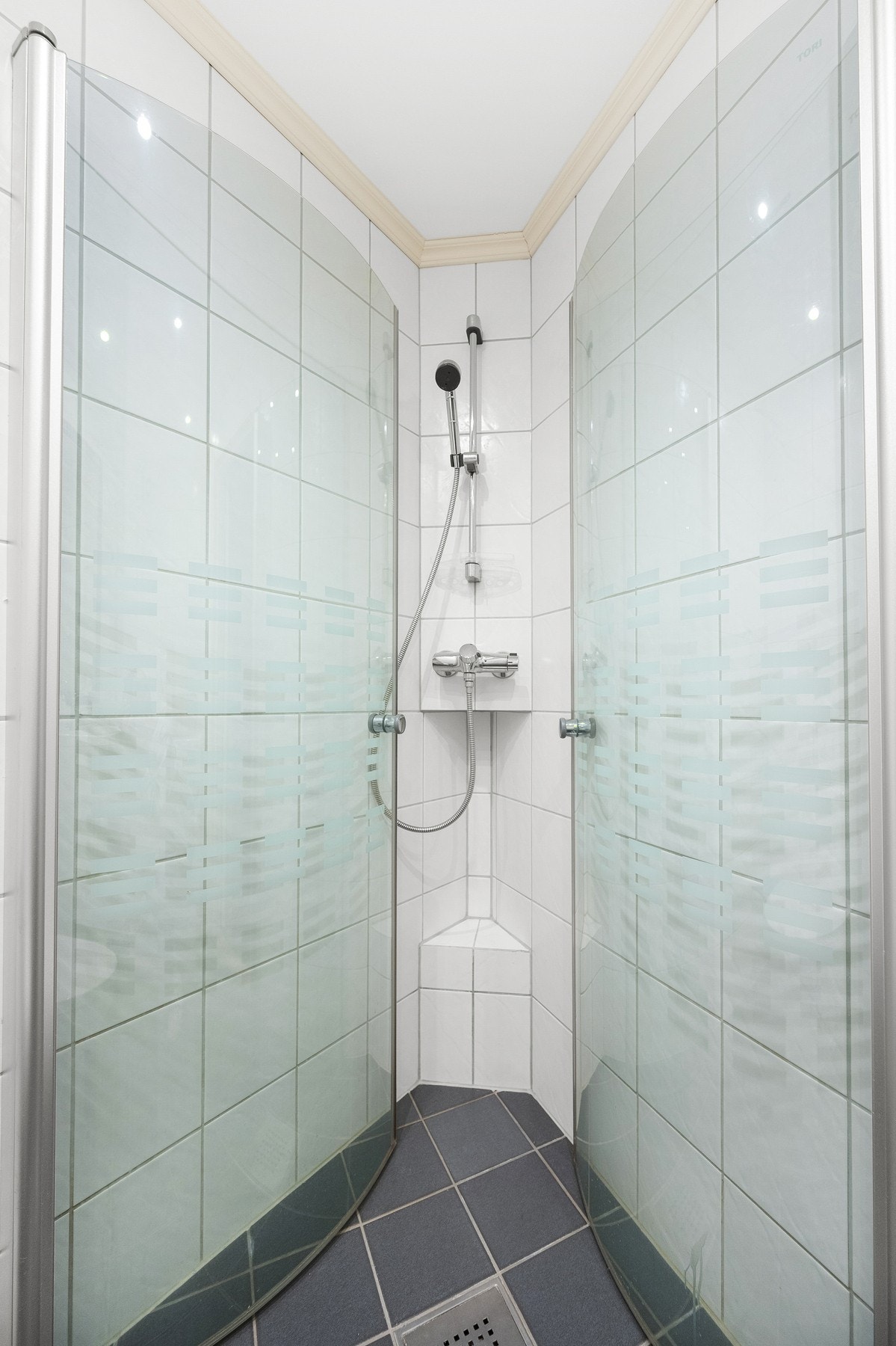 Videre inneholder badet dusjhjørne med innfellbare dusjdører og gulvstående toalett. Galleribilde