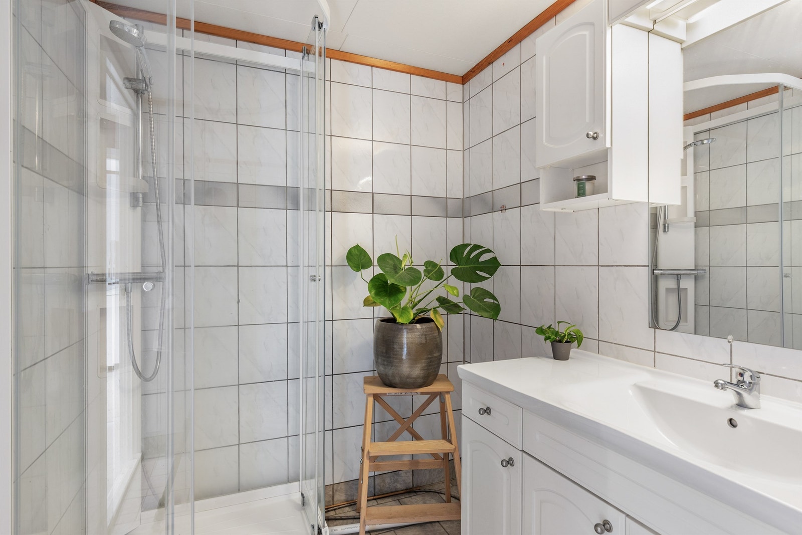Badet i 2. etasje er flislagt på gulv og vegger med elektrisk gulvvarme. Badet er innredet med dusjkabinett, servant med innredning, speil med skap og skapinnredning. Galleribilde