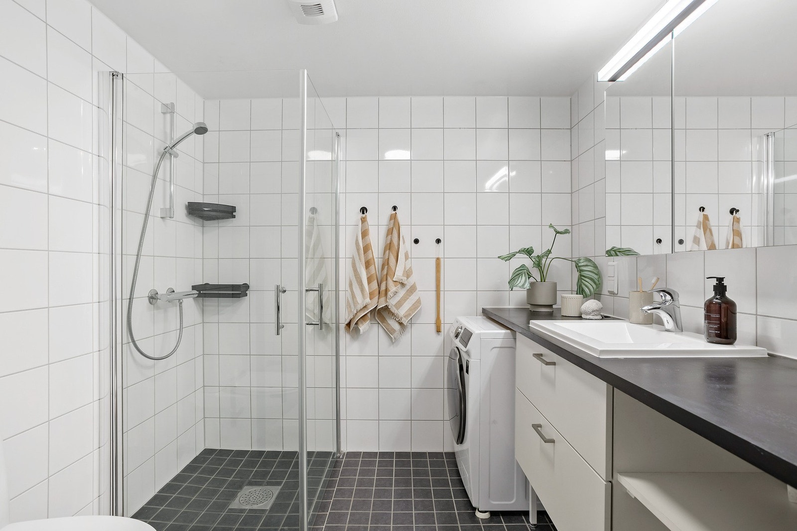 Badet er pent flislagt og av romslig størrelse. Det er elektriske varmekabler i gulvet og opplegg for vaskemaskin Galleribilde