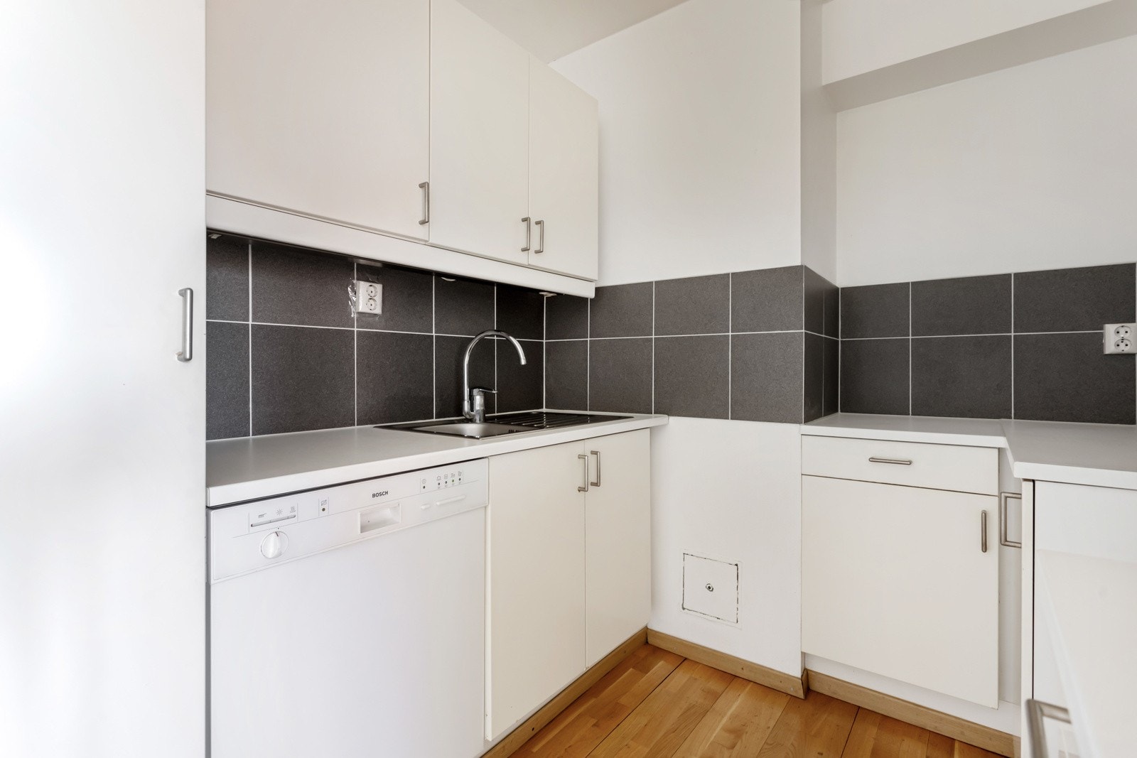 Ikea kjøkkeninnredning fra ca. 2000 med glatte fronter, laminat benkeplate, oppvaskkum, opplegg til oppvaskmaskin og fliser over kjøkkenbenk. Galleribilde