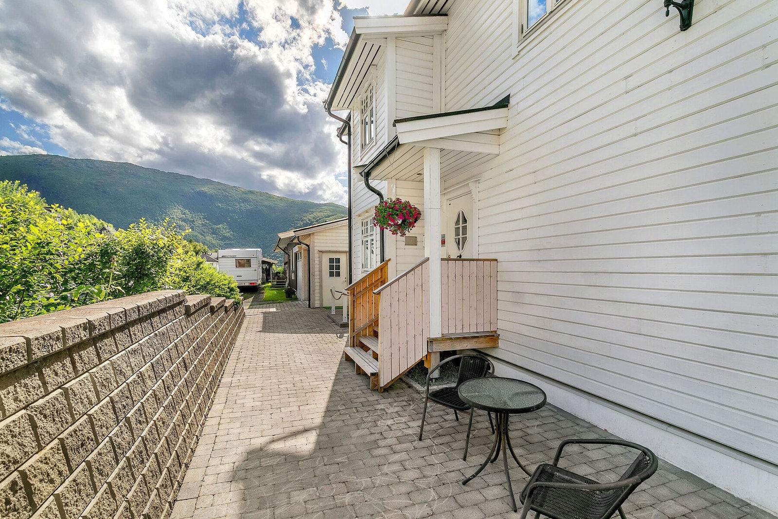 Pent anlagt uteområde på forsiden med brostein og støttemur Galleribilde