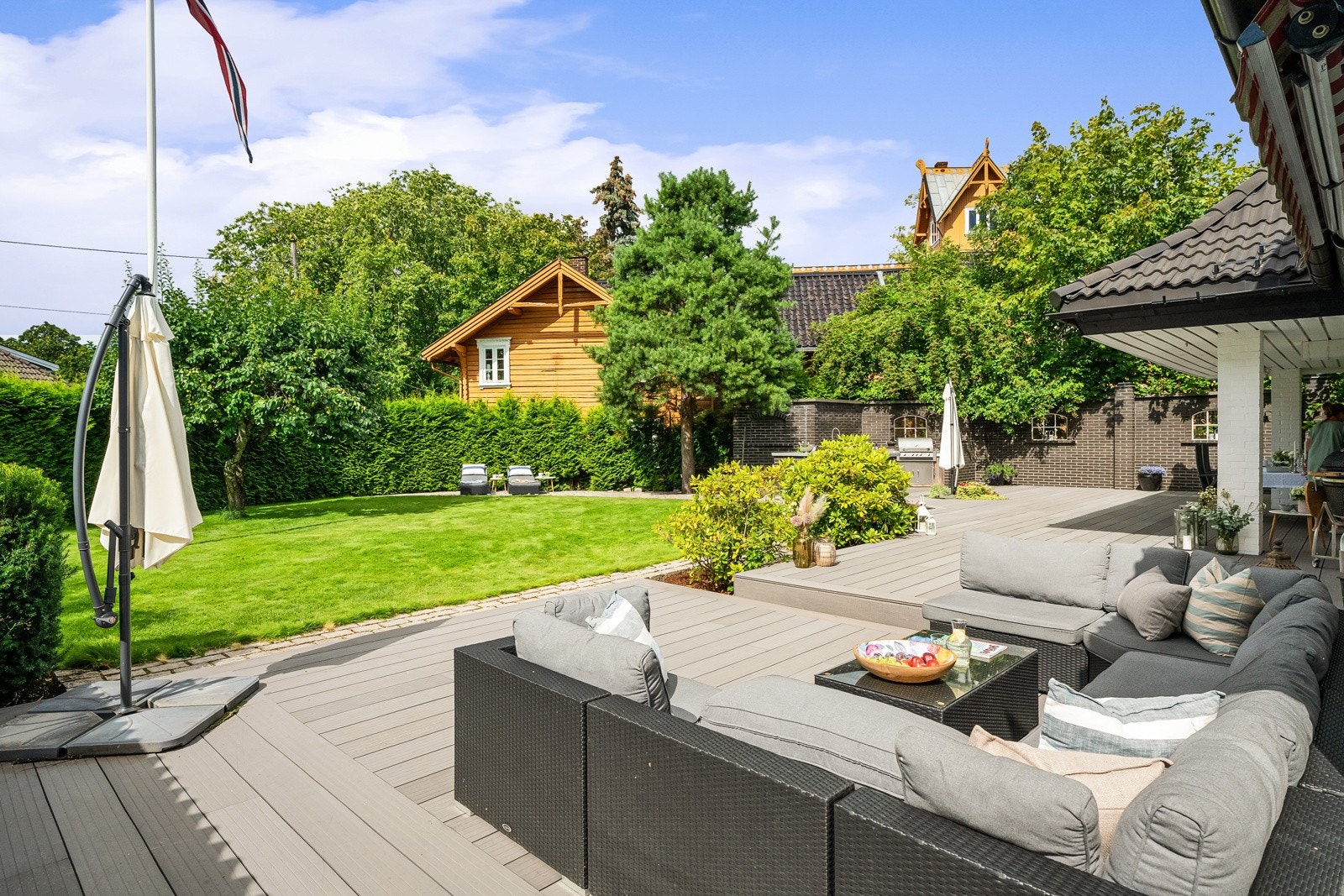 Det er lagt pen, kantet brostein mellom plenen og terrassen. Galleribilde