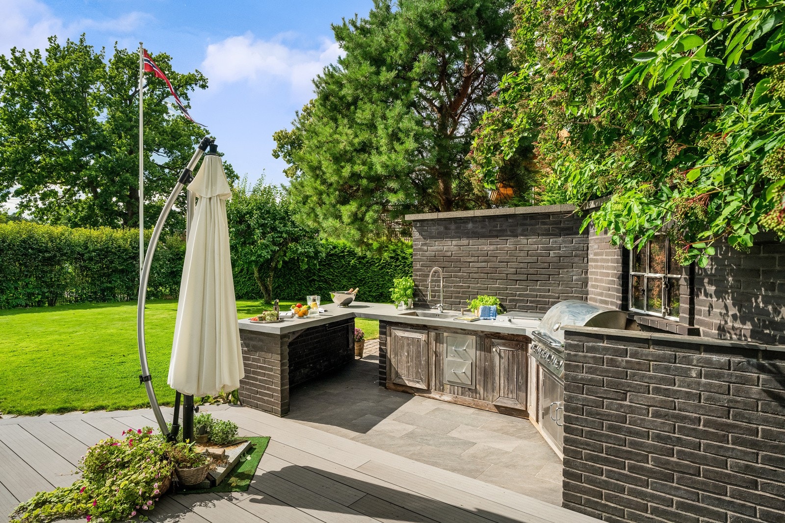 Påkostet utekjøkken med godt benkeareal, skapfronter i tre og flislagt dekke. Galleribilde