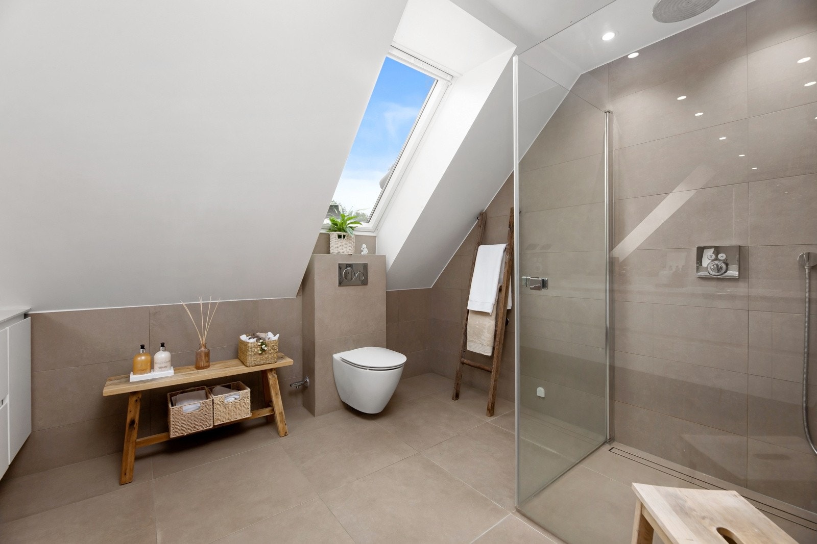 Veggmontert toalett med spylekran, og en flott dusjnisje med innfellbare glassdører. Det er tilrettelagt for badekar. Galleribilde