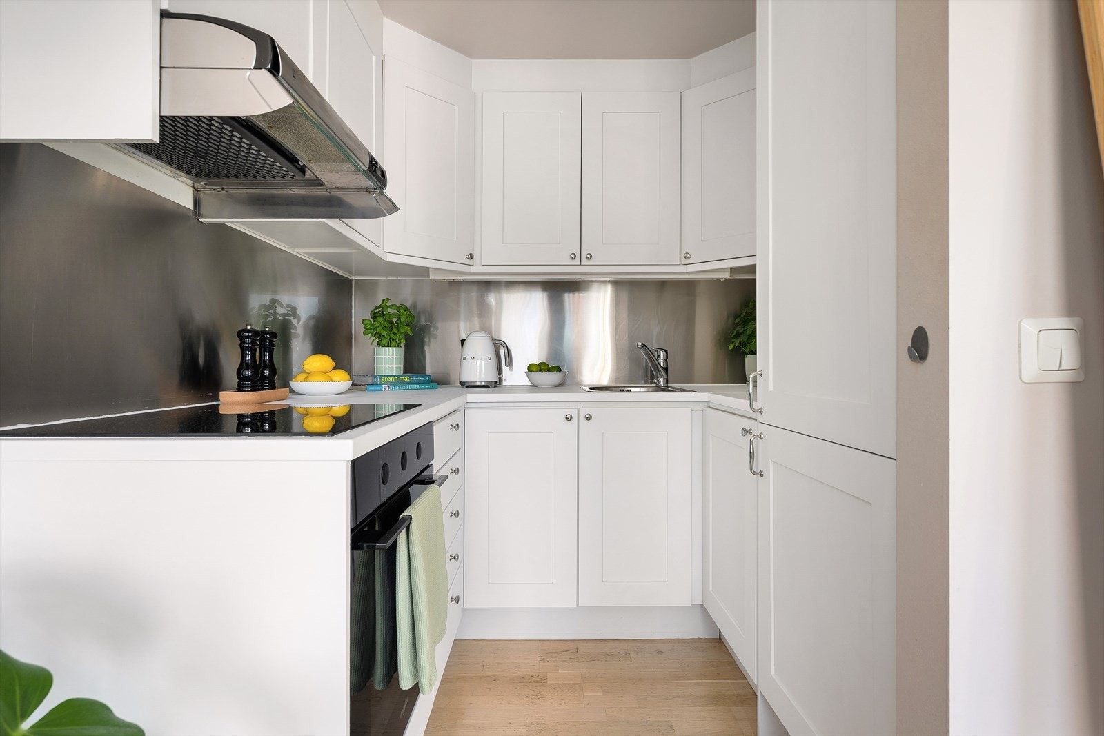 Pent kjøkken, innredet med integrert kjøleskap, platetopp, integrert stekeovn, lyse fronter samt laminat benkeplate Galleribilde