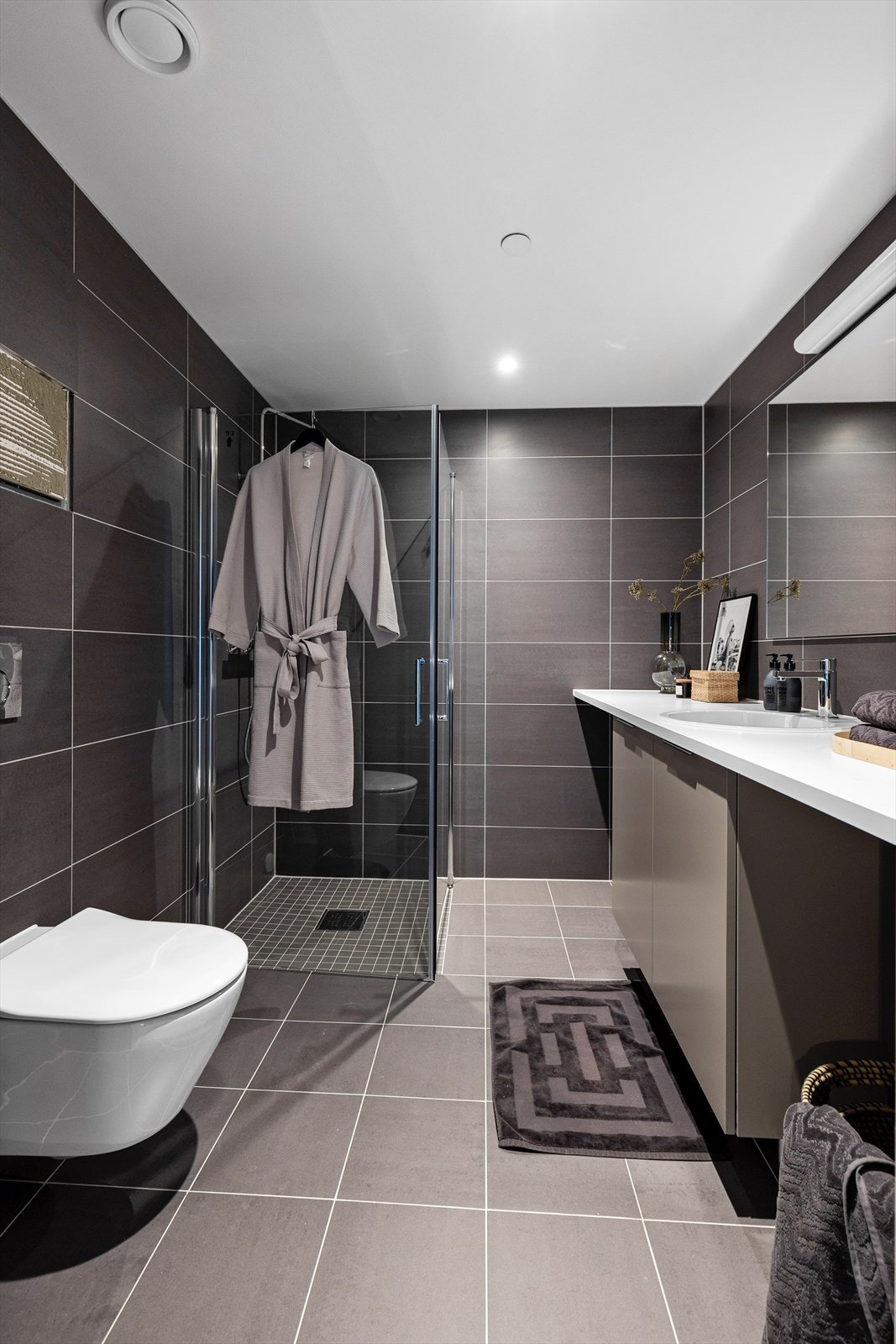 Flislagt bad med vegghengt WC og romslig dusjnisje Galleribilde