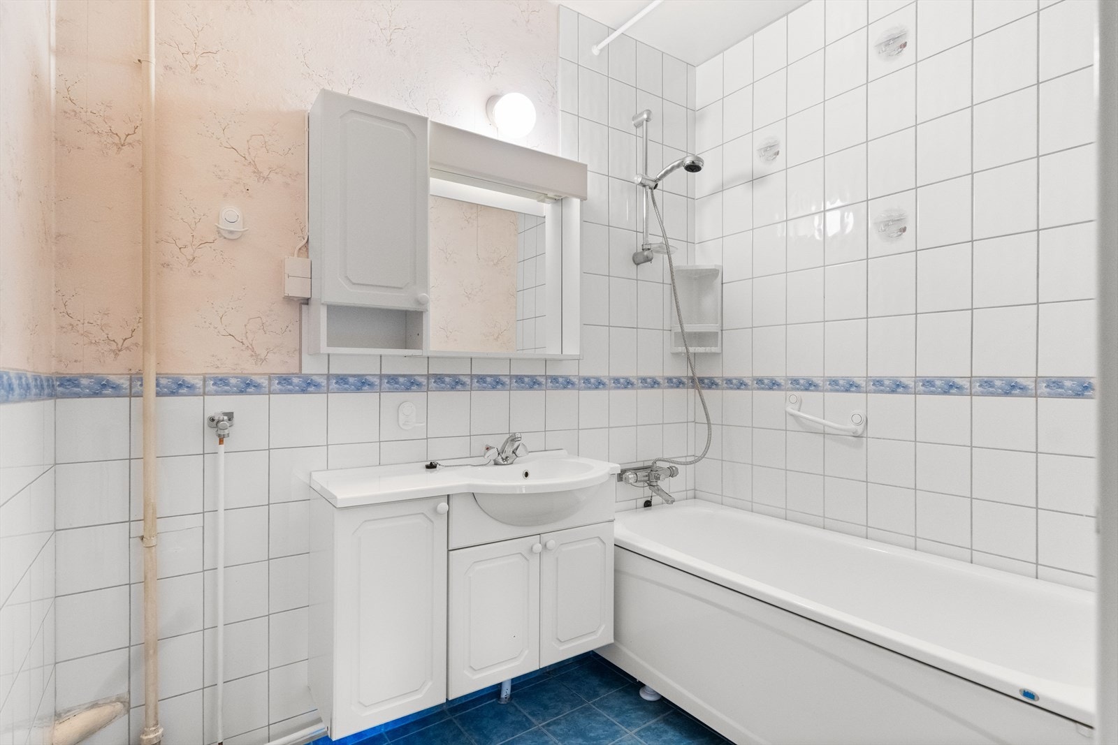 Badet har fliser på gulv og vegger samt opplegg for vaskemaskin. Galleribilde