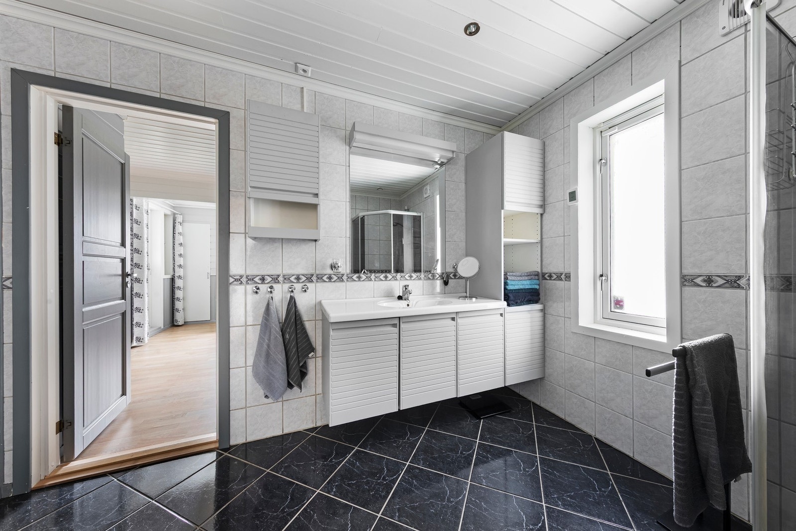 Bad i 1. etasje har flislagt gulv med varmekabler, baderomsinnredning med nedfelt servant og dusjhjørne Galleribilde