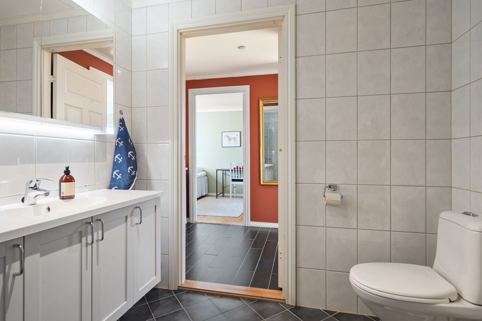 Badet er innredet med servant på skap, dusj hjørnet og gulv montert vannklosett. Galleribilde