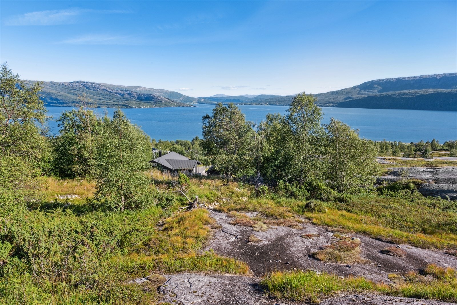 Unik tomt med naturlig badeland i bakgården og skikjøring til langt ut i juni på majestetiske Mjølkåtinden og Tortenviktinden. Galleribilde