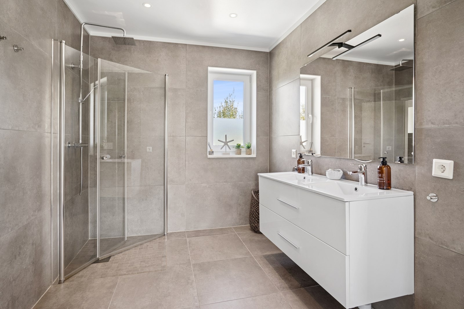 Baderommet er innredet med dobbel servant nedfelt i innredningen, toalett og dusjhjørne med svingbare dører. Galleribilde