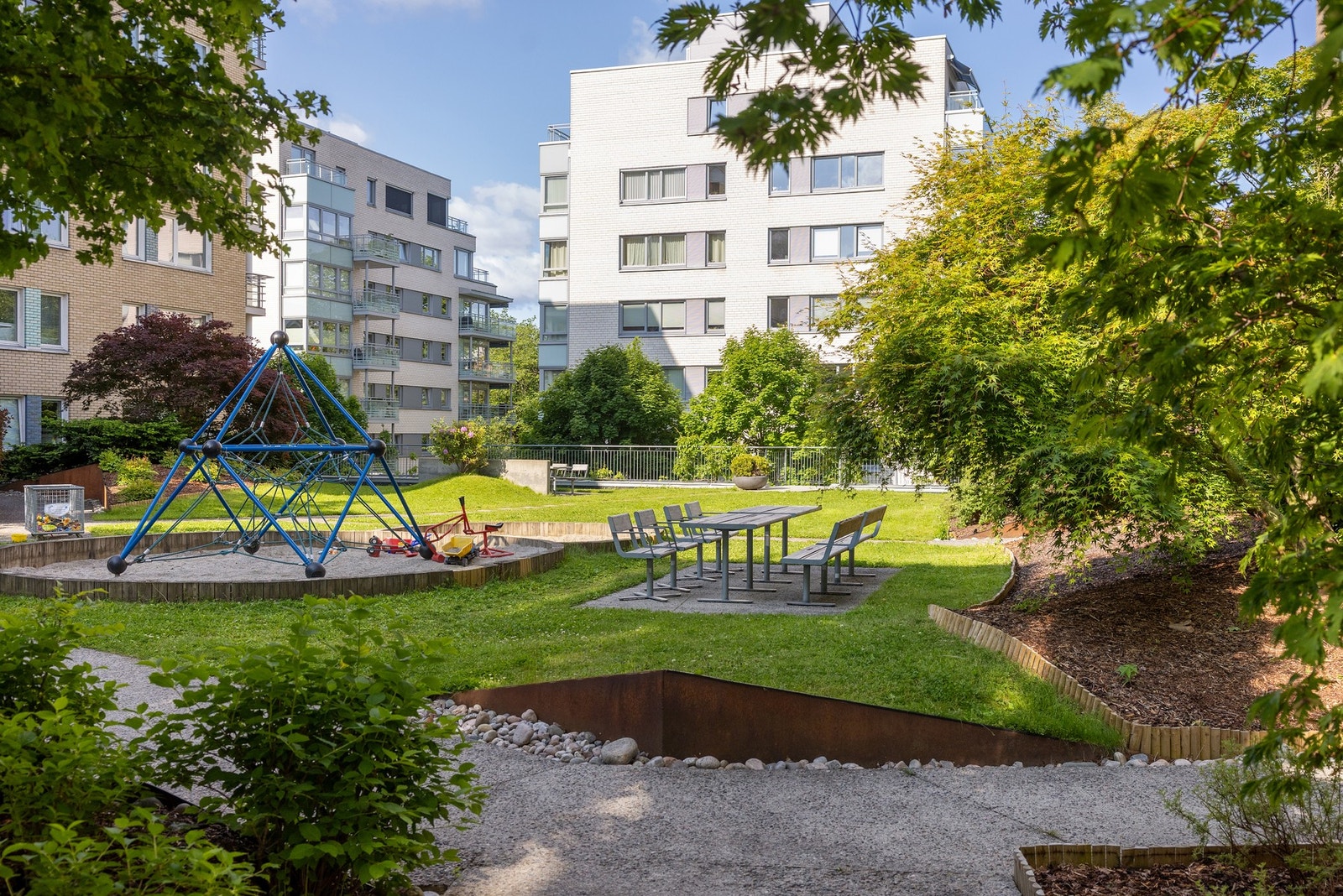 Velholdt og solrik felleshage med sitteplasser og lekeplass. Galleribilde