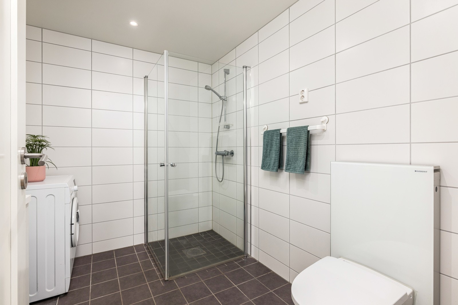 Badet er innredet med dusjhjørne, servantinnredning, toalett & opplegg for vaskemaskin. Galleribilde