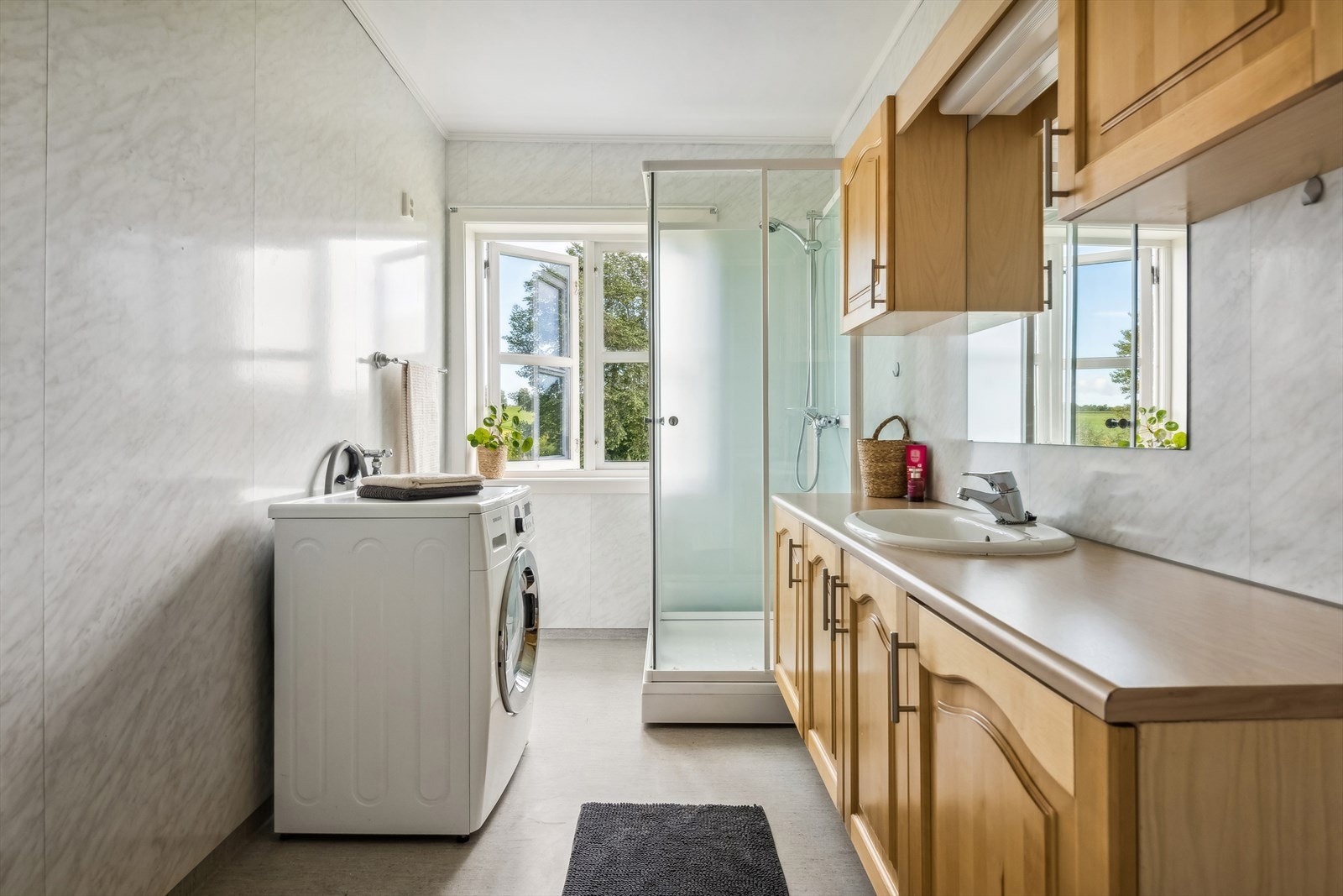 Romslig baderom innredet med speil, servant med underskap, her har du god lagring, videre er det toalett og dusjkabinett. Opplegg for vaskemaskin. Galleribilde