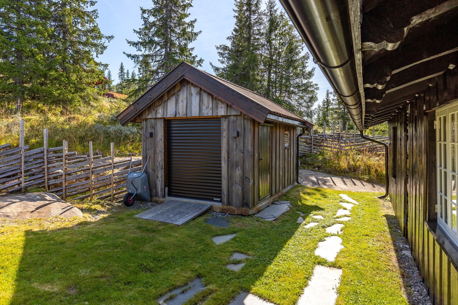 Det frittstående bod-/uthusbygget fra 2019 har elektrisk leddport i front og vanlig inngangsdør på siden. Galleribilde