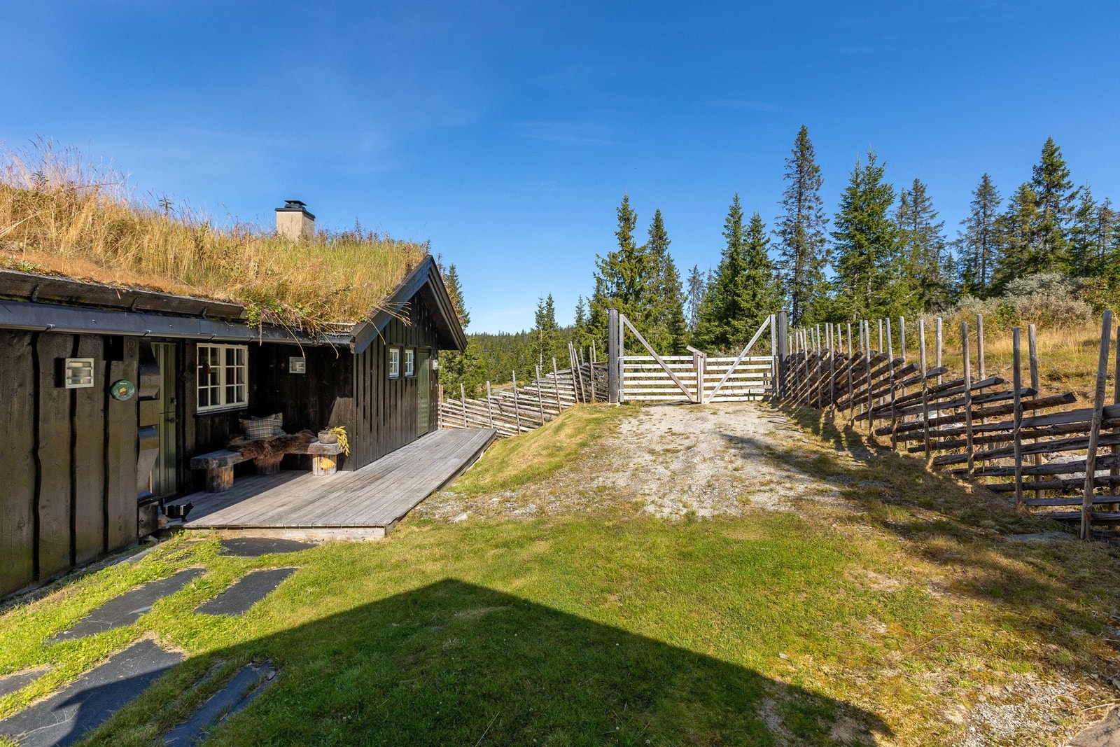 Tomta er pent opparbeidet med gressplen rundt hytta kombinert med naturlig vegetasjon som glir fint inn i fjellandskapet. Galleribilde