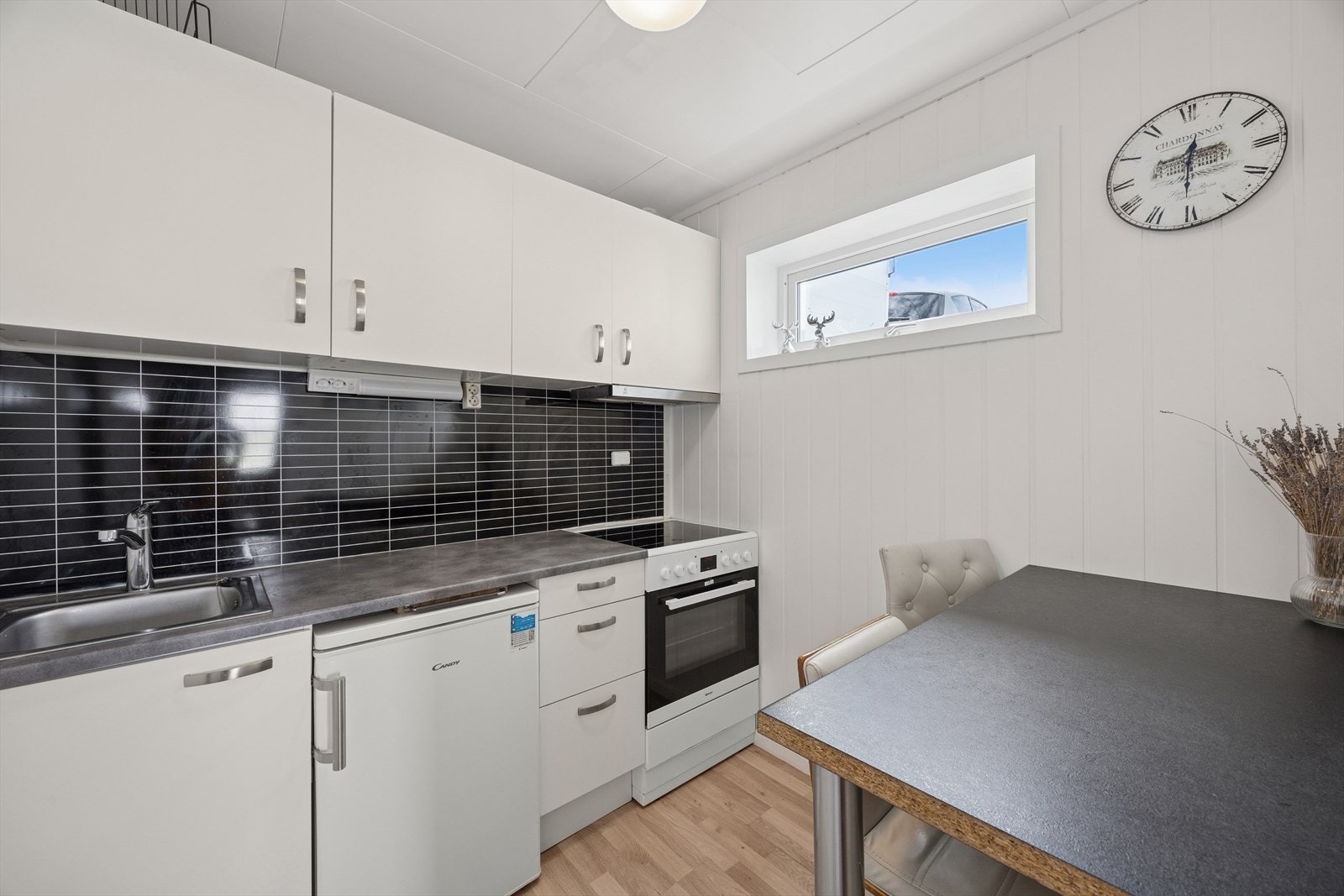 Et funksjonelt kjøkken med komfyr med platetopp og oppvaskmaskin. Galleribilde