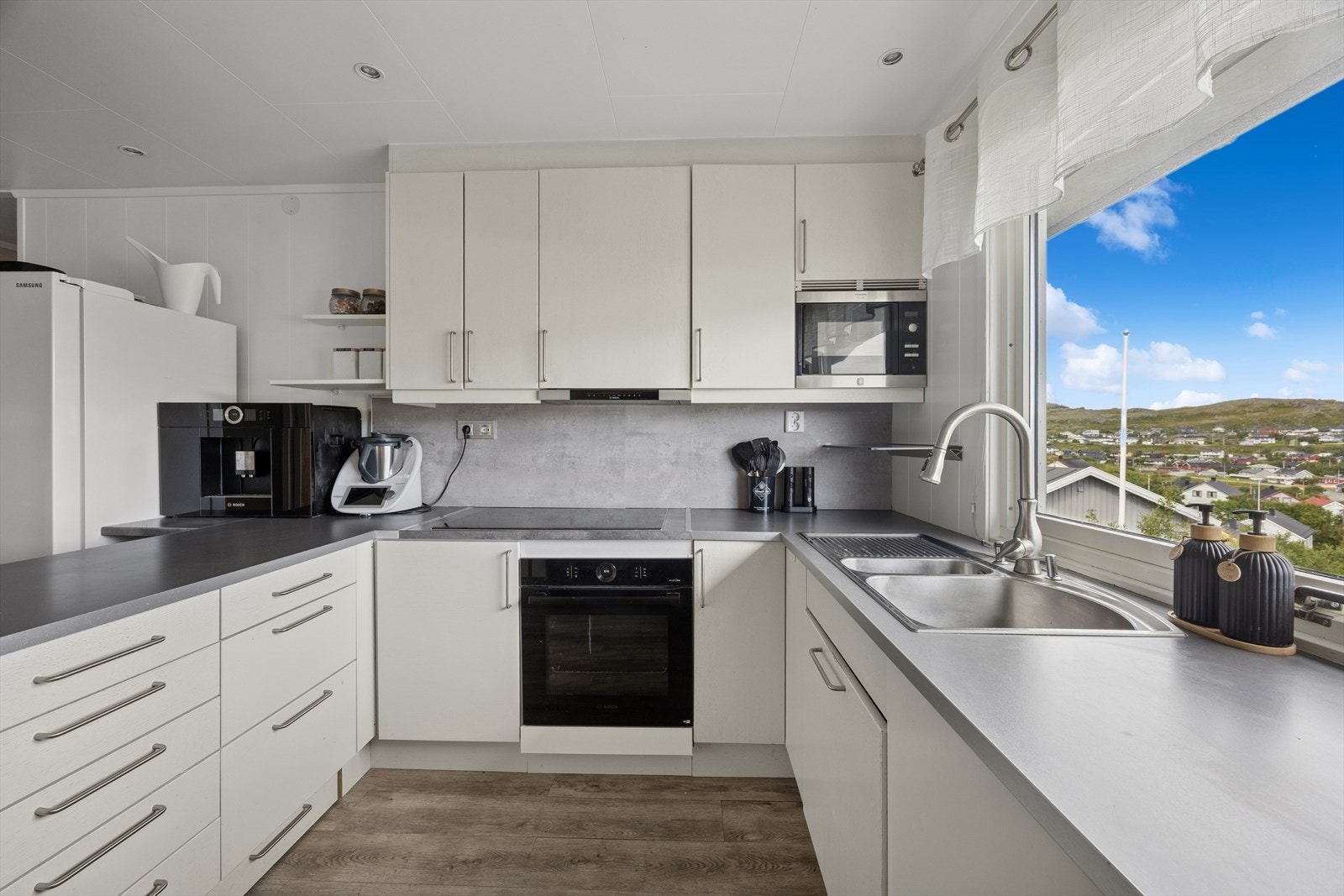 Kjøkkenet ble oppgradert i 2017 og fremstår moderne med glatte fronter og laminat benkeplate som gir et rent og tidløst uttrykk. Stort vindu som inviterer den nydelige utsikten inn. Galleribilde