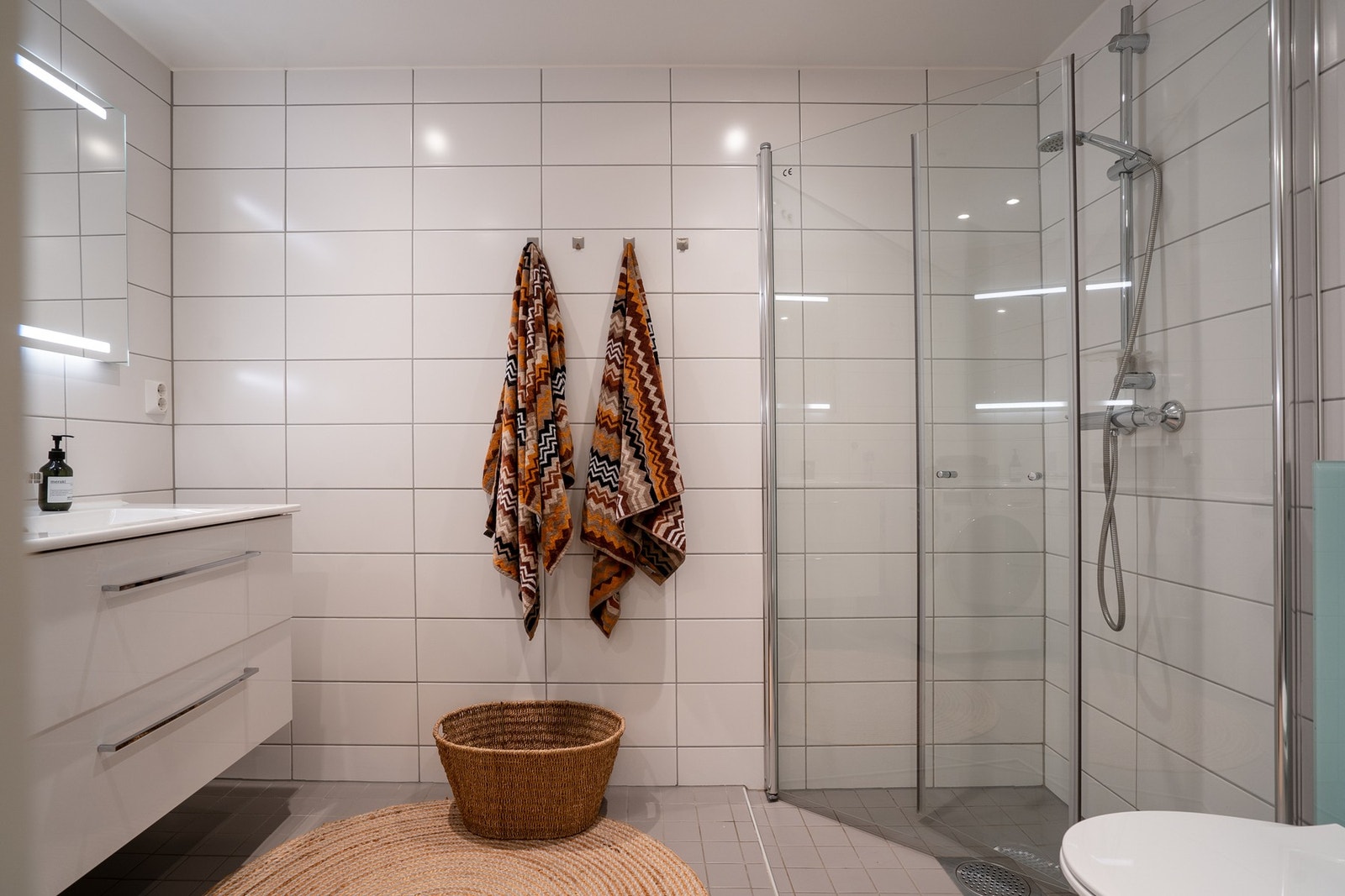 Boligens baderom med inngang fra entréen er i likhet med det andre baderommet pent flislagt og har varme i gulv. Det er opplegg for vaskemaskin og plass til tørketrommel. Galleribilde