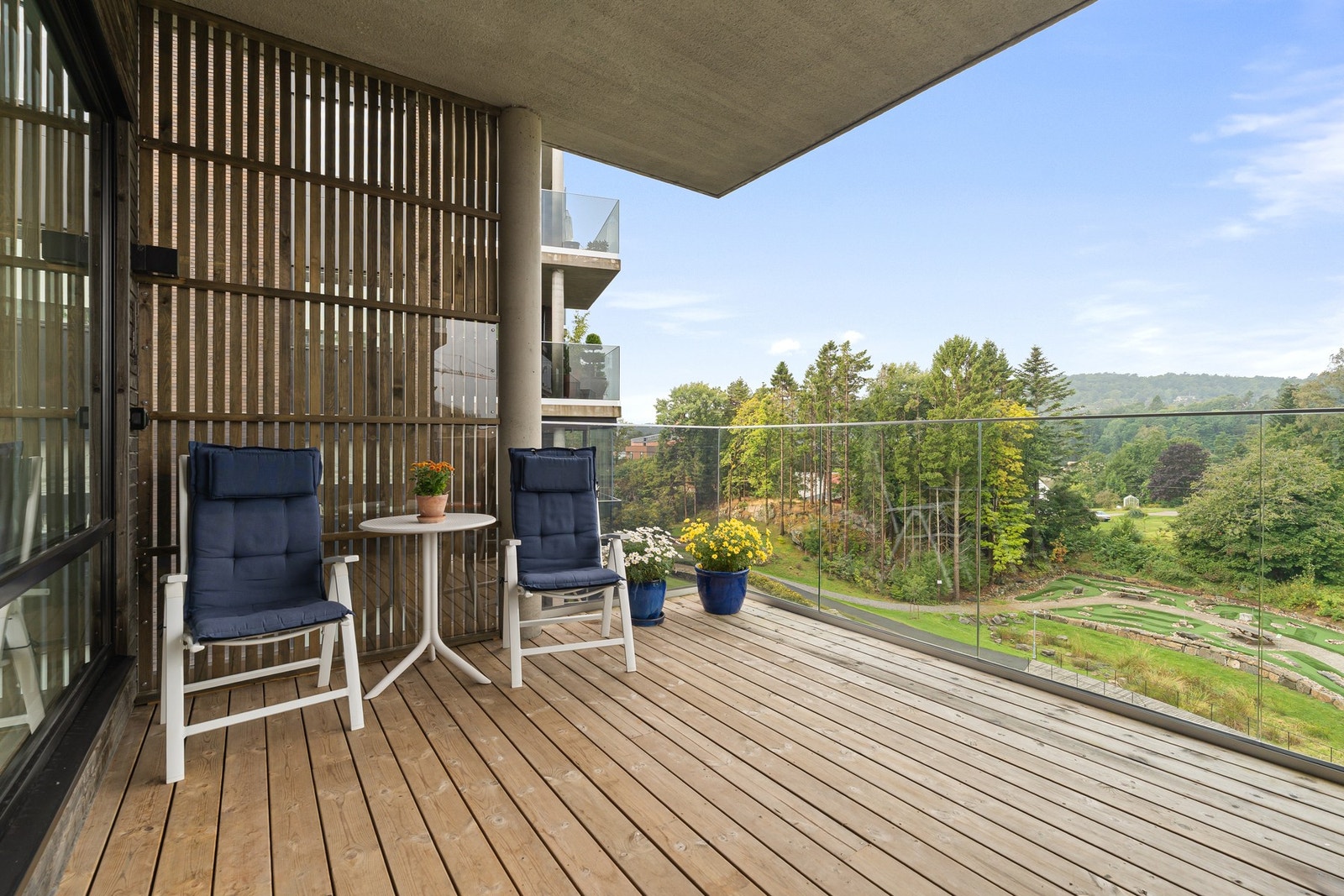 Solfylt og overbygd balkong med utsikt til fint uteareal med minigolfbane Galleribilde