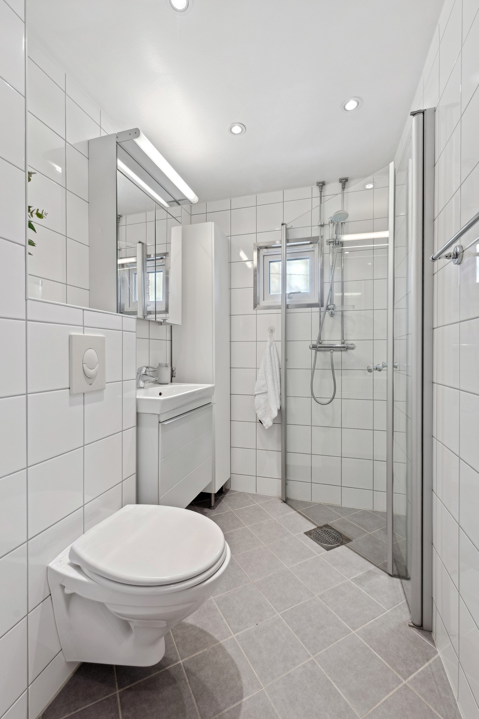 Pent bad med gulvvarme og downlights, samt inn- utadslående dusjvegger, servant med underskap og overskap med speilfronter og overlys. Galleribilde