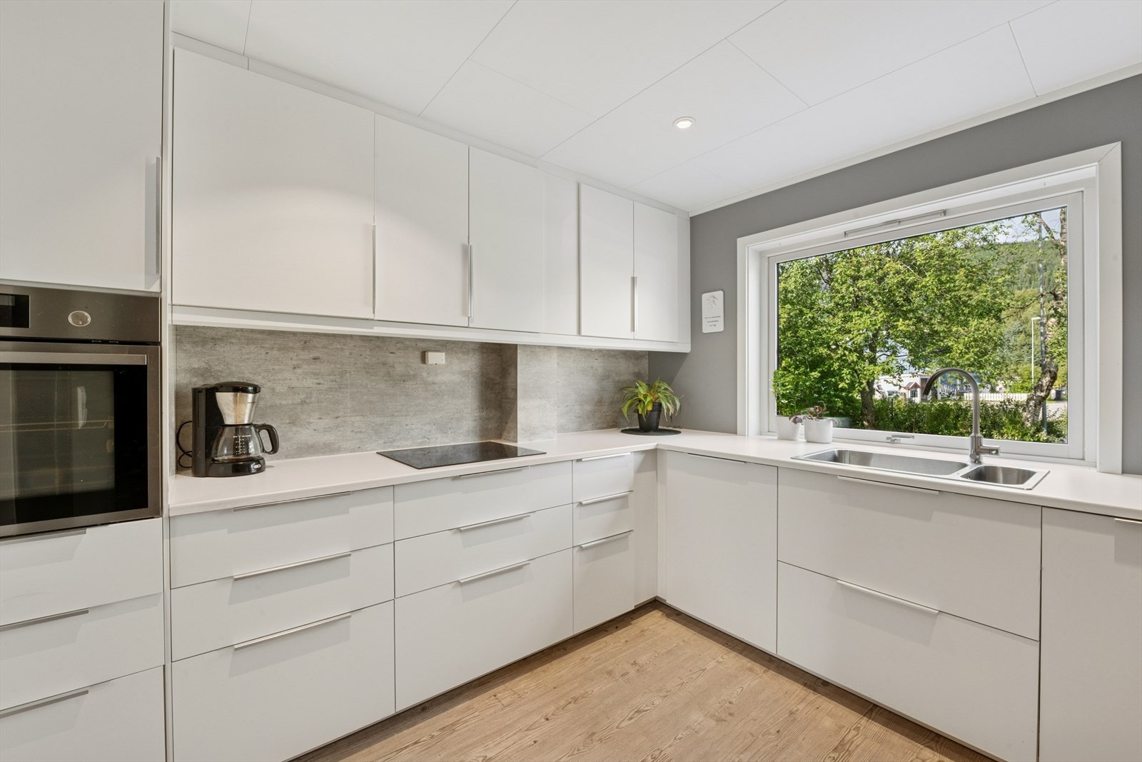 Flott moderne kjøkken som har rikelig med skap og benkeplass. Kjøkkenet er utstyrt med hvitevarer som kjøl/fryseskap, oppvaskmaskin, induksjonstopp med komyrvakt og stekeovn Galleribilde