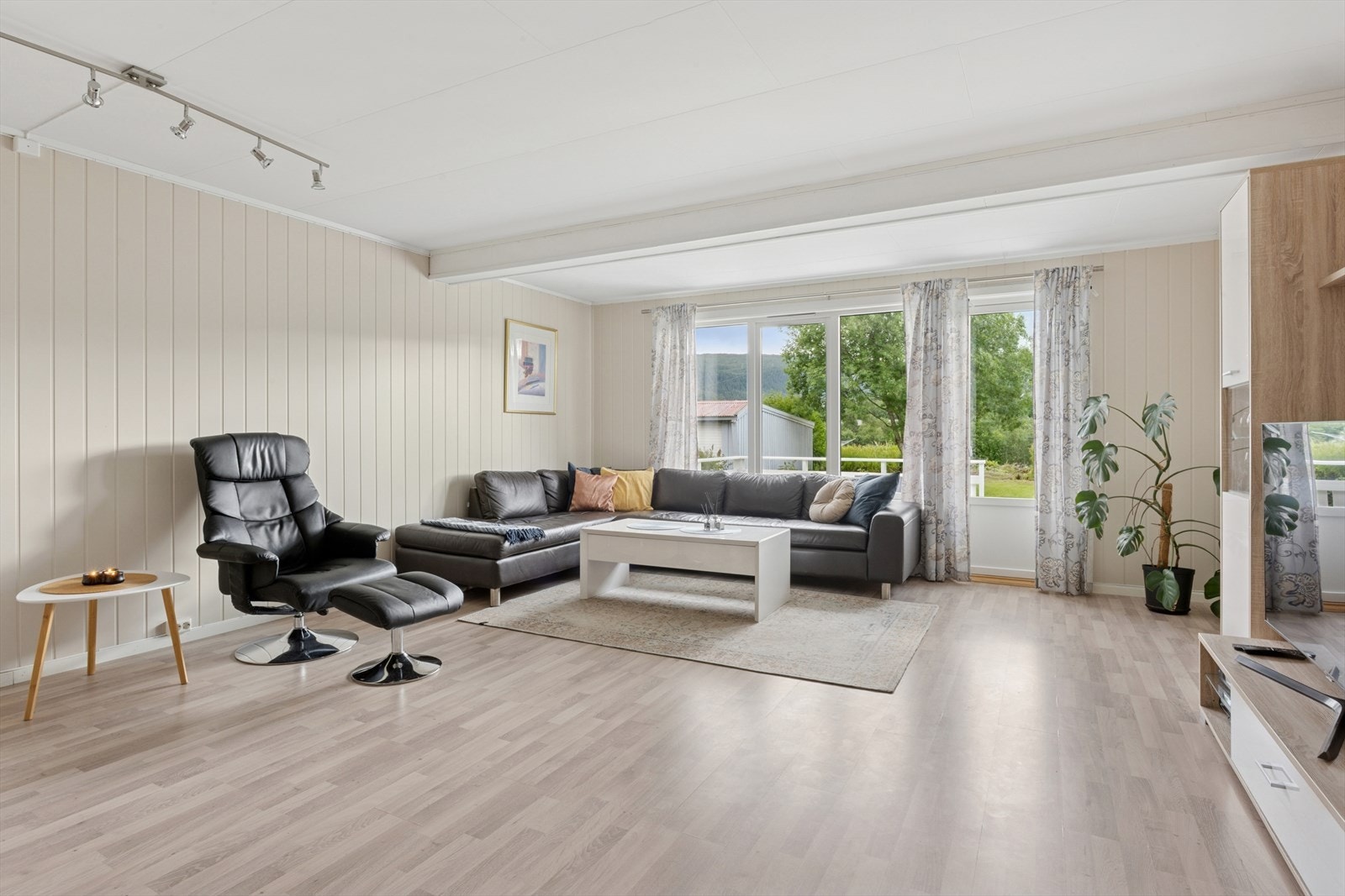 Stor romslig stue som fremstår som lys og innbydende med stilrene flotte overflater Galleribilde