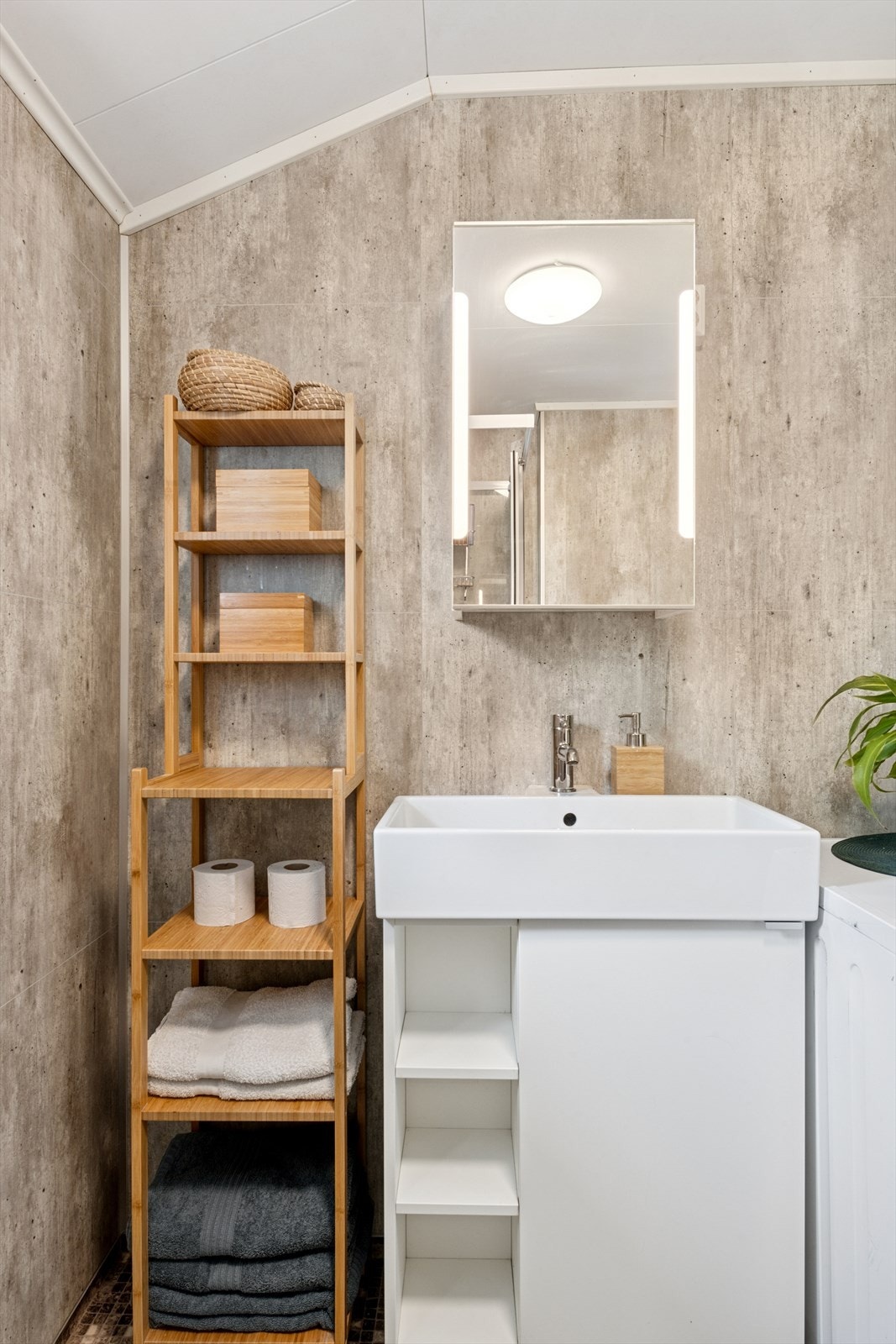 Innredning med hvit rektangulær vask, montert på et funksjonelt underskap. Speilskap med integrert belysning. Galleribilde