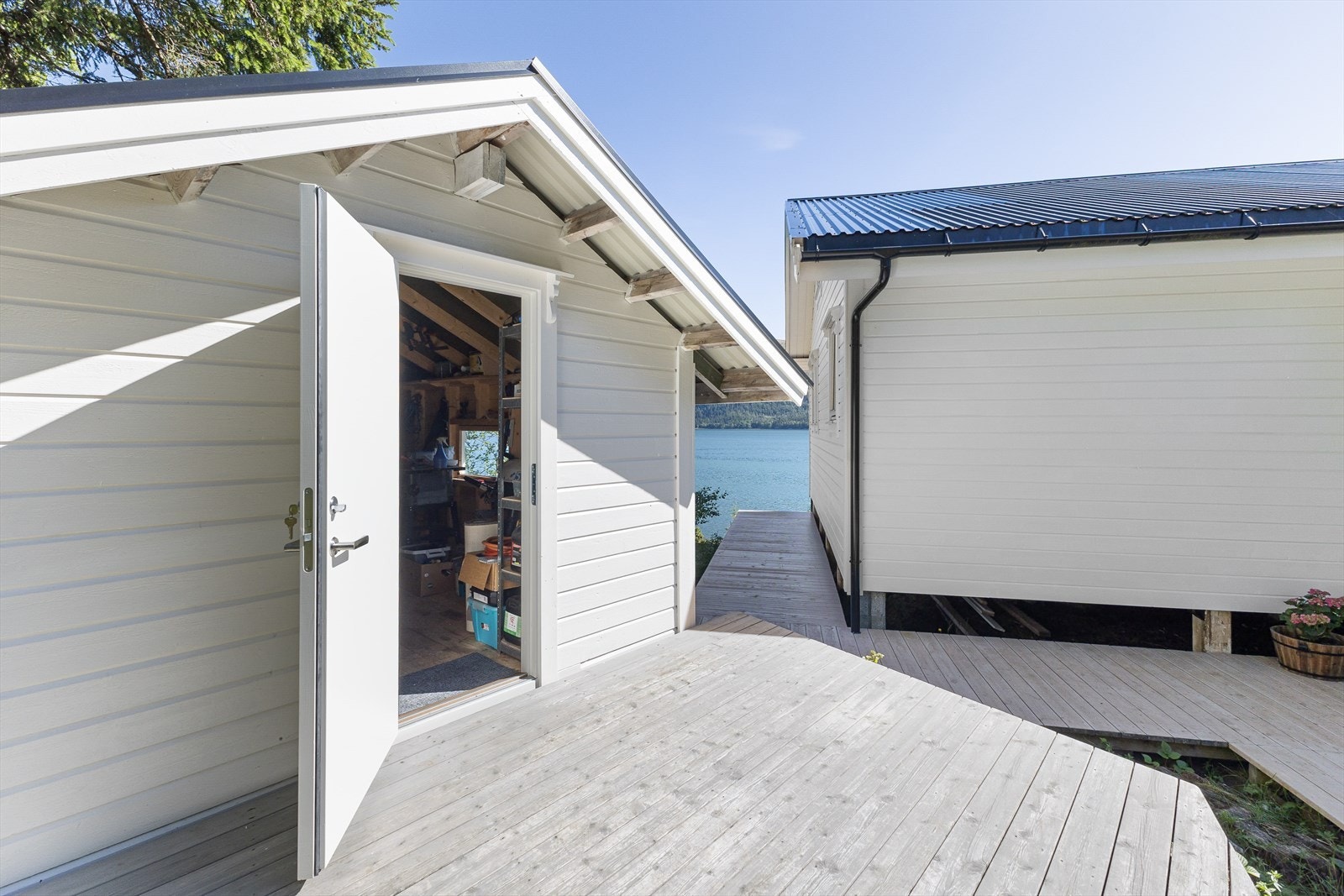 Uthus på 11 m² med terrasse på 8 m². Man kan gå stort sett tørrskodd rundt hytta, da det er lagt terrasser/plattinger for å komme seg til de fleste bygg. Galleribilde