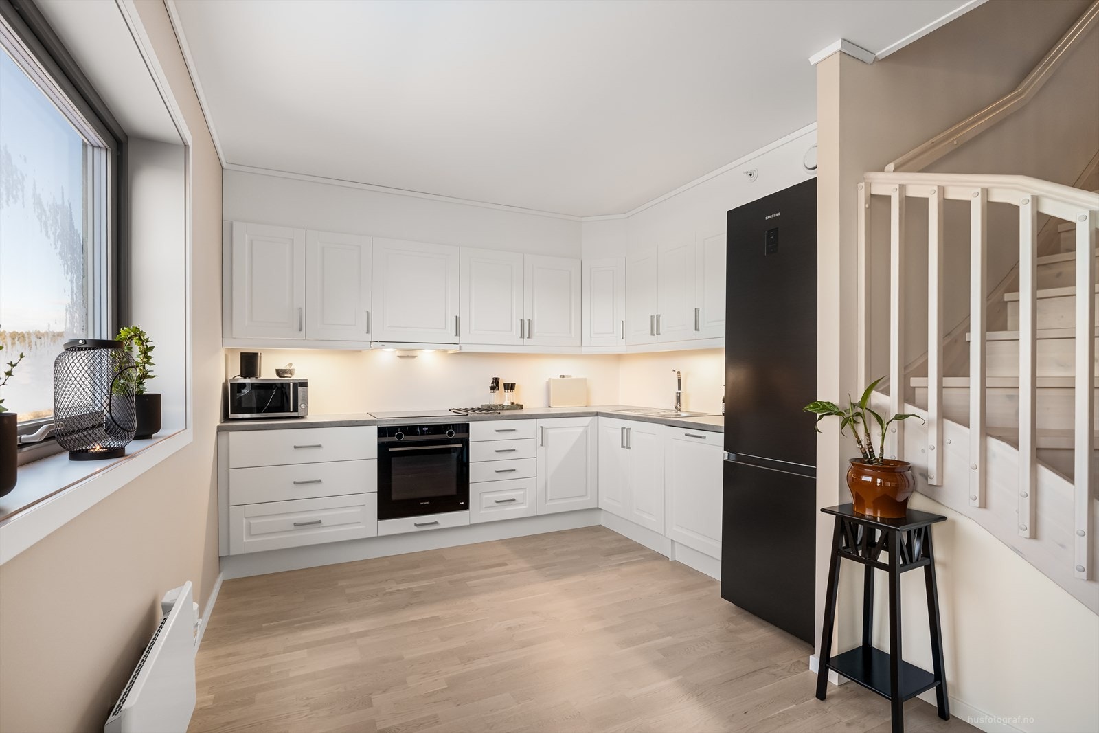 Klassisk og elegant kjøkkeninnredning med hvite profilerte fronter og benkeplate av laminat. Galleribilde