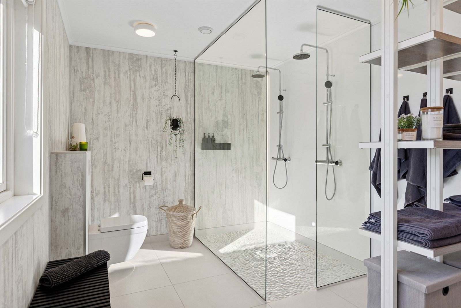 Badet er innredet med dobbelt servant på servantskap, dusjvegger i glass og vegghengt toalett, som gir både funksjonalitet og et stilrent uttrykk. Galleribilde