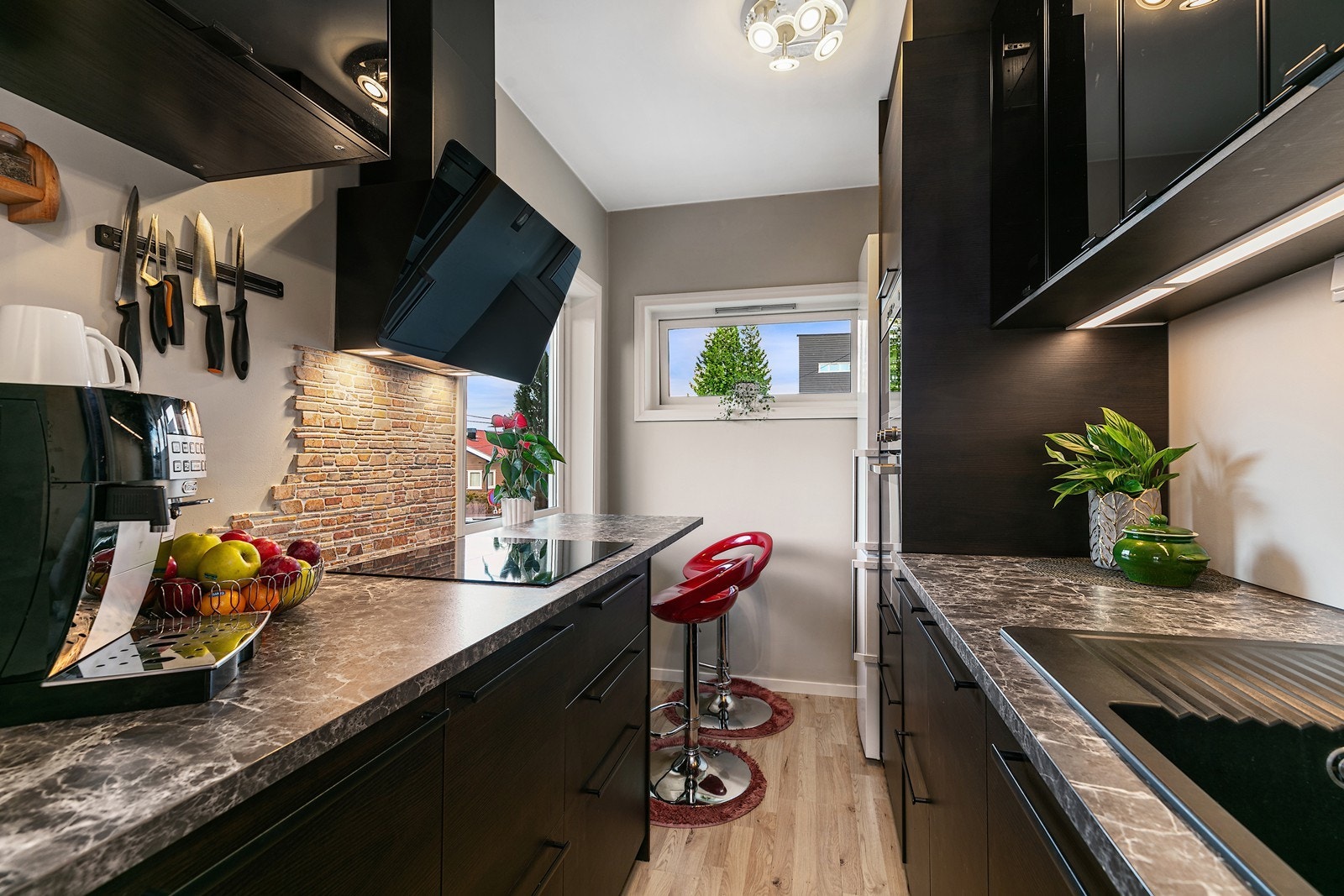 Stilrent og moderne kjøkken med mørk kjøkkeninnredning og integrerte hvitevarer. Galleribilde