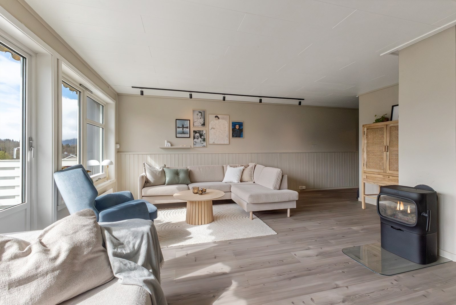 Romslig stueløsning med lyssskinne i himling, vedovn og pene, moderne farger. Galleribilde