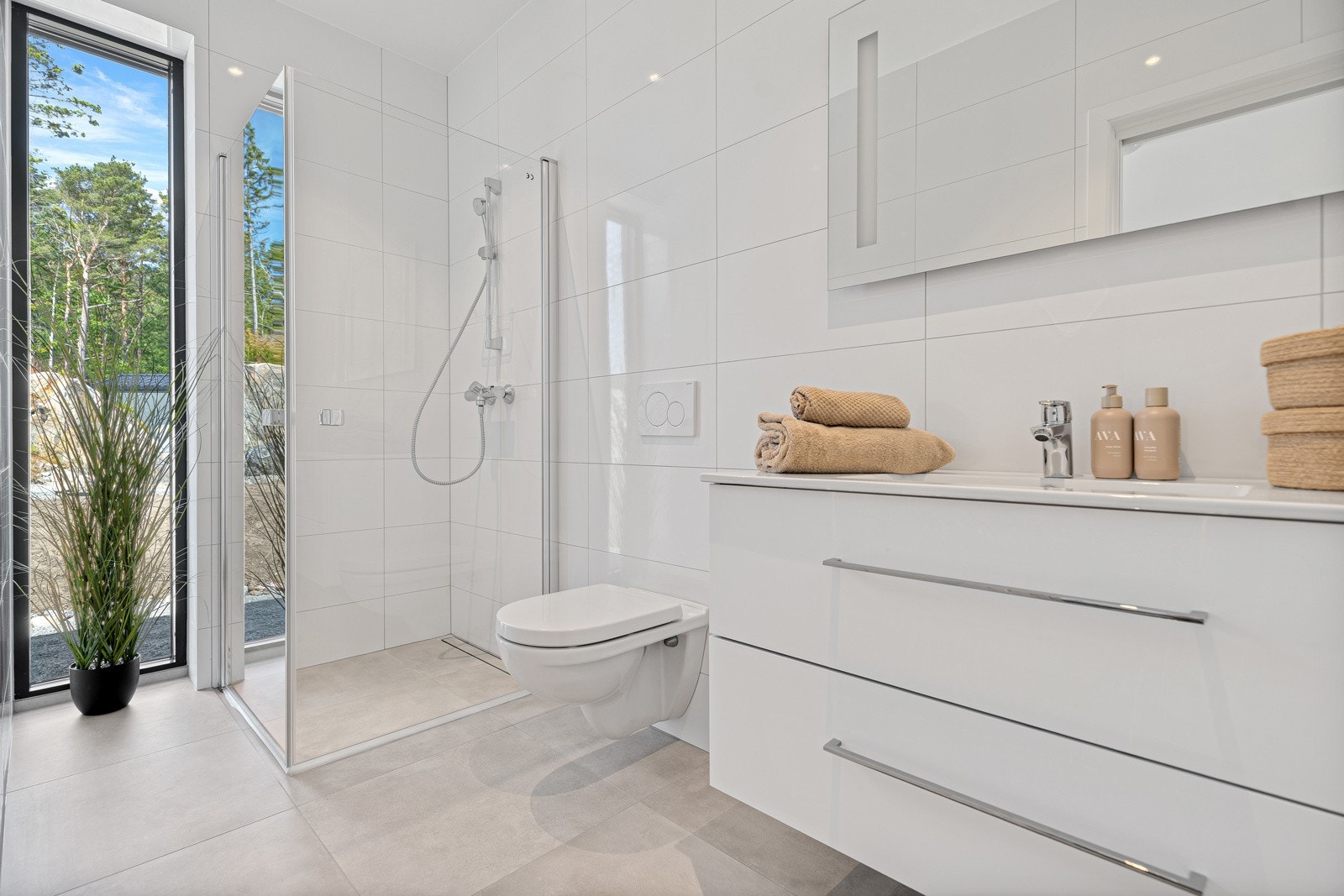 Delikat baderom med dusjhjørne, vegghengt toalett og bred servant. Det er varmekabler i gulvet. Galleribilde