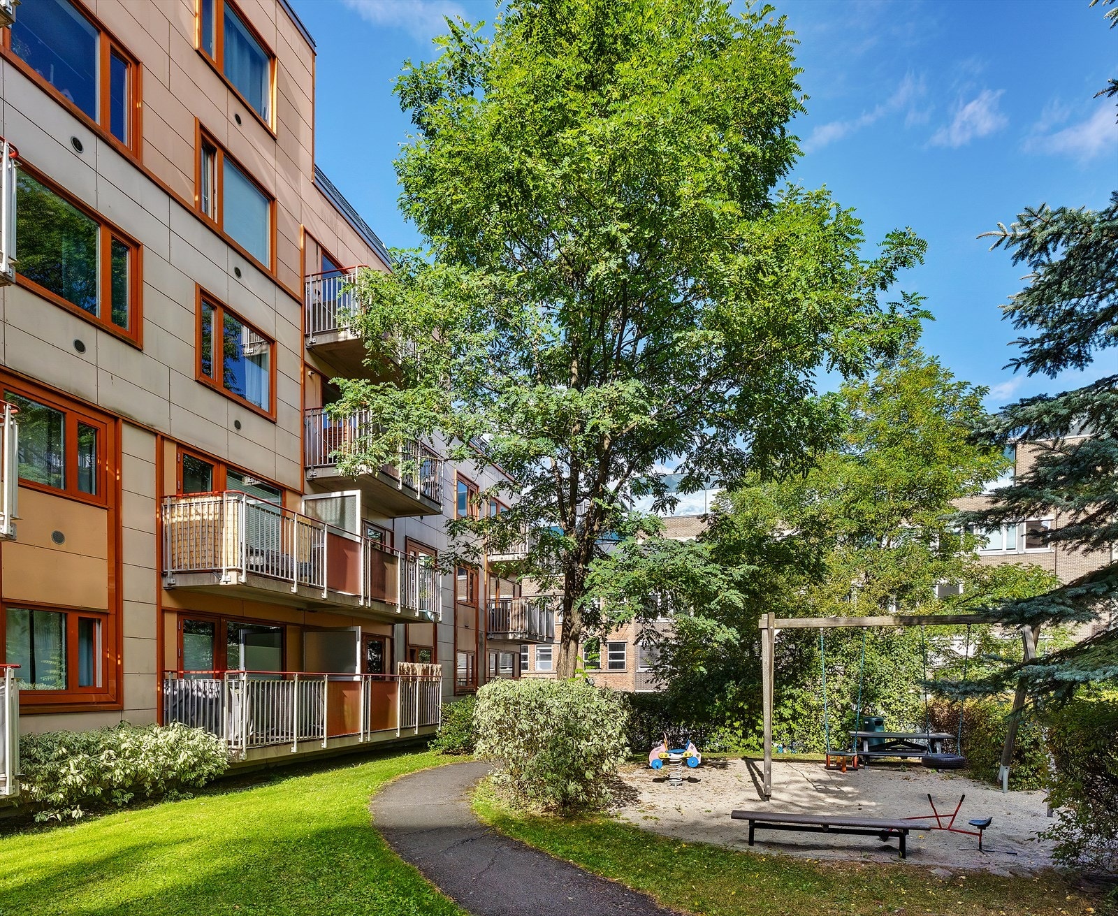 Felles tomt for borettslaget opparbeidet med blant annet asfalterte internstier, gressplen, sittegrupper, lekeapparater, sykkelstativer, trær, prydbusker og diverse beplantning. Galleribilde