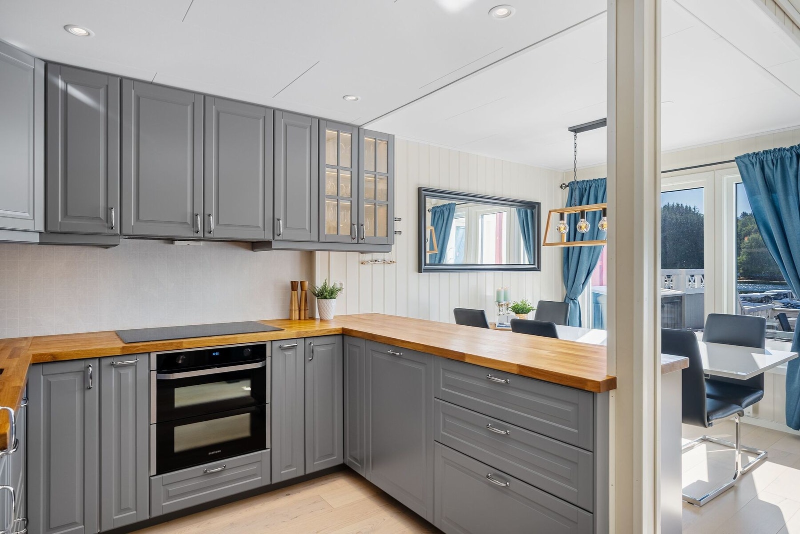 Kjøkkendelen har downlights i himling og praktisk halvøy ut mot spisestue Galleribilde