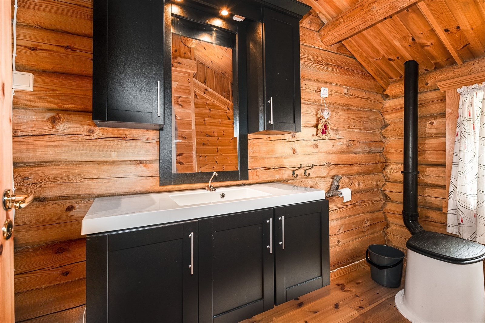 Fint hygienerom med lakkerte furugulv og overflater med laftet tømmer. Galleribilde